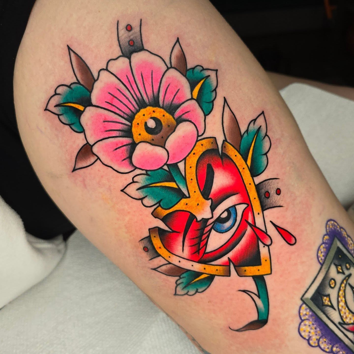 Mask and flower American traditional tattoo on the thigh by Justin Eldridge