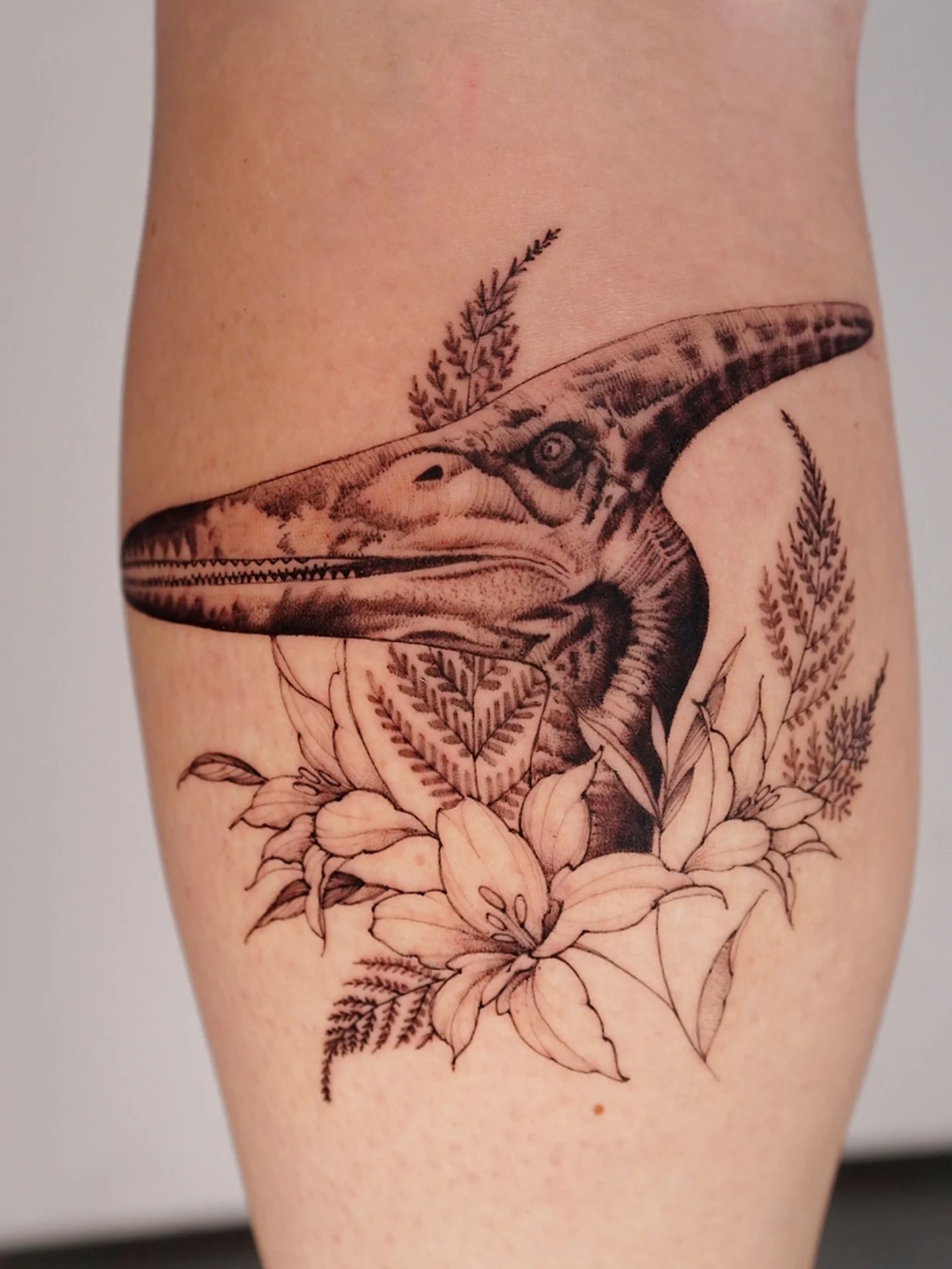 Pterodactyl and flowers realism tattoo on the forearm by Vii