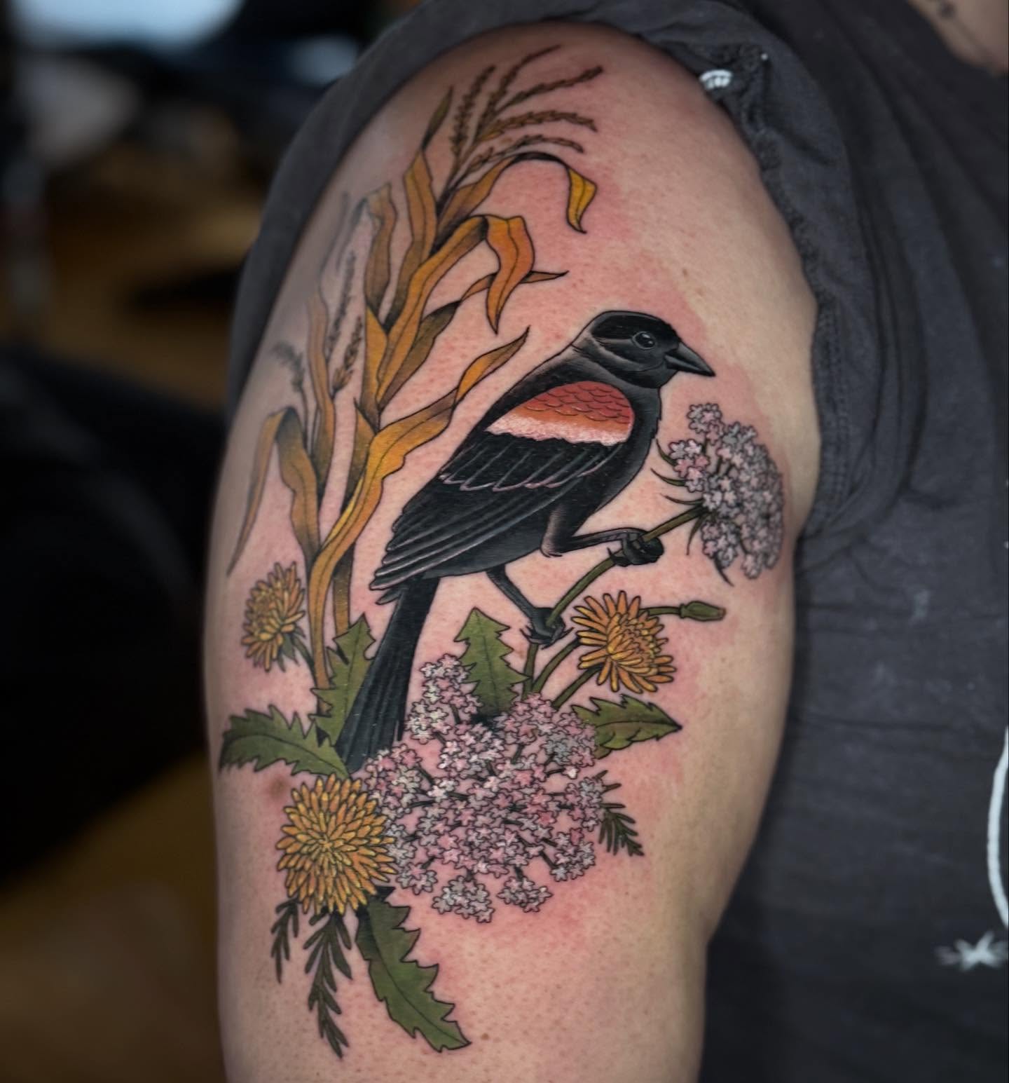 Red-winged blackbird and wildflowers American traditional tattoo on the shoulder by Katy Bisby