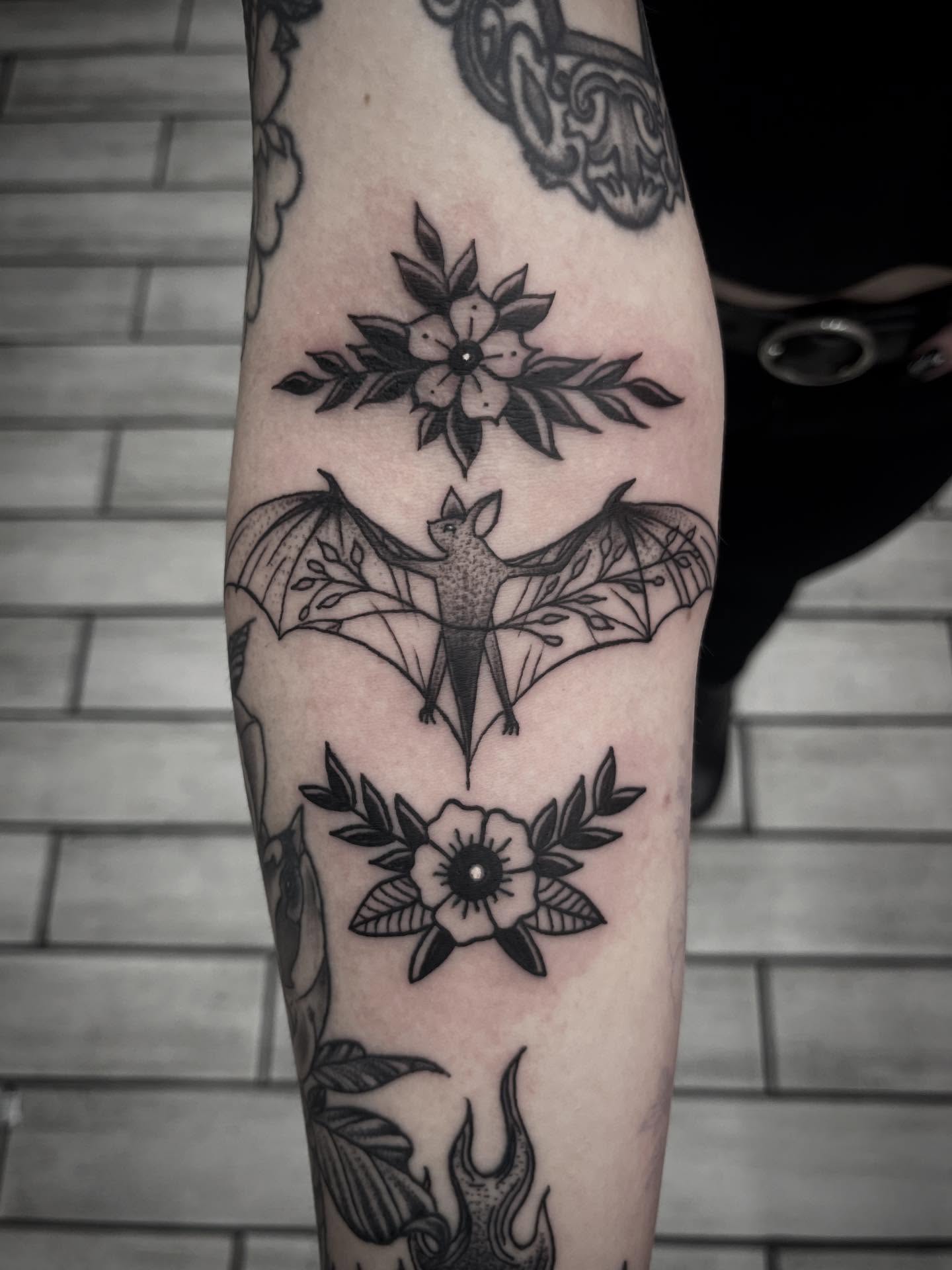 Bat and flowers black and grey tattoo on the forearm by Sean Gallagher