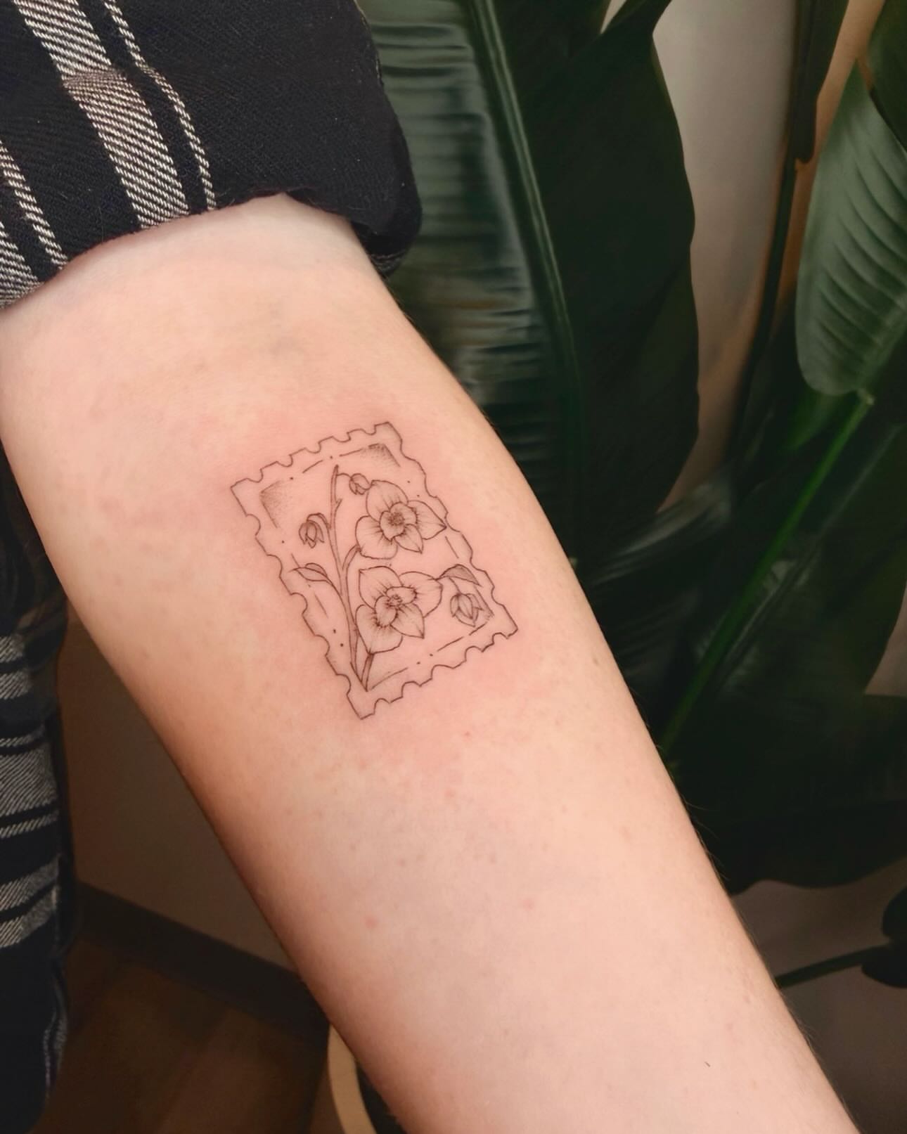 Ticket with flowers black and grey tattoo on the forearm by Ashley Pilgreen