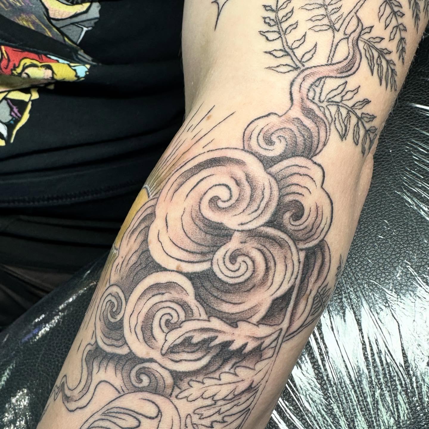 Swirling clouds black and grey tattoo on the forearm by Sarah Nash