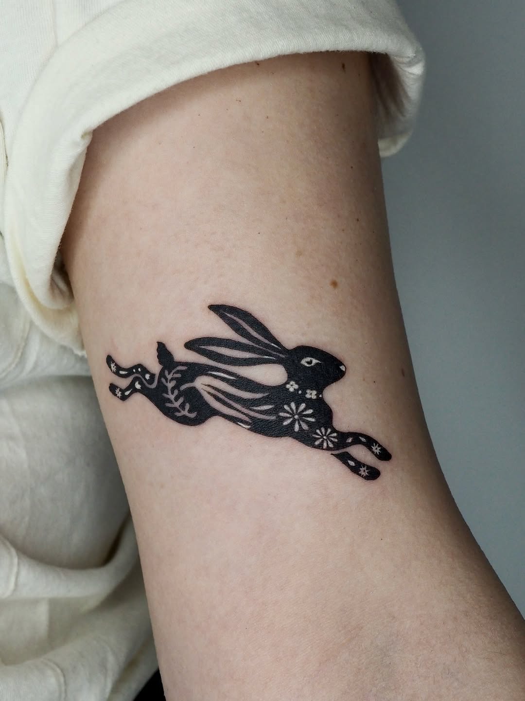 Rabbit with floral patterns fine line tattoo on the forearm by A. Eye Tat