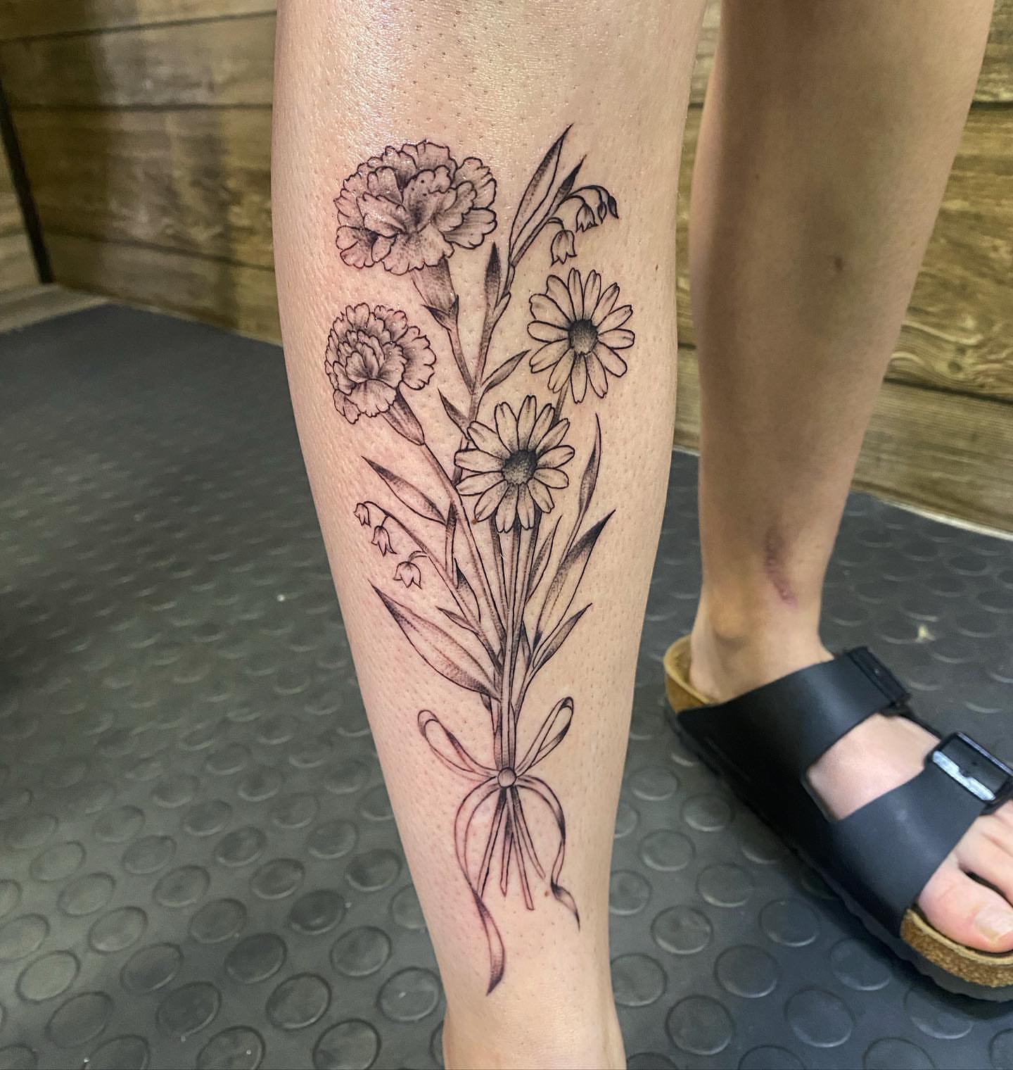 Flowers black and grey tattoo on the calf by Spencer Jones Tattoos