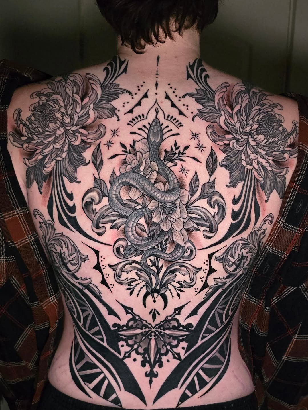 Snake and chrysanthemum geometric tattoo on the back by Jack Daniel Knowlden