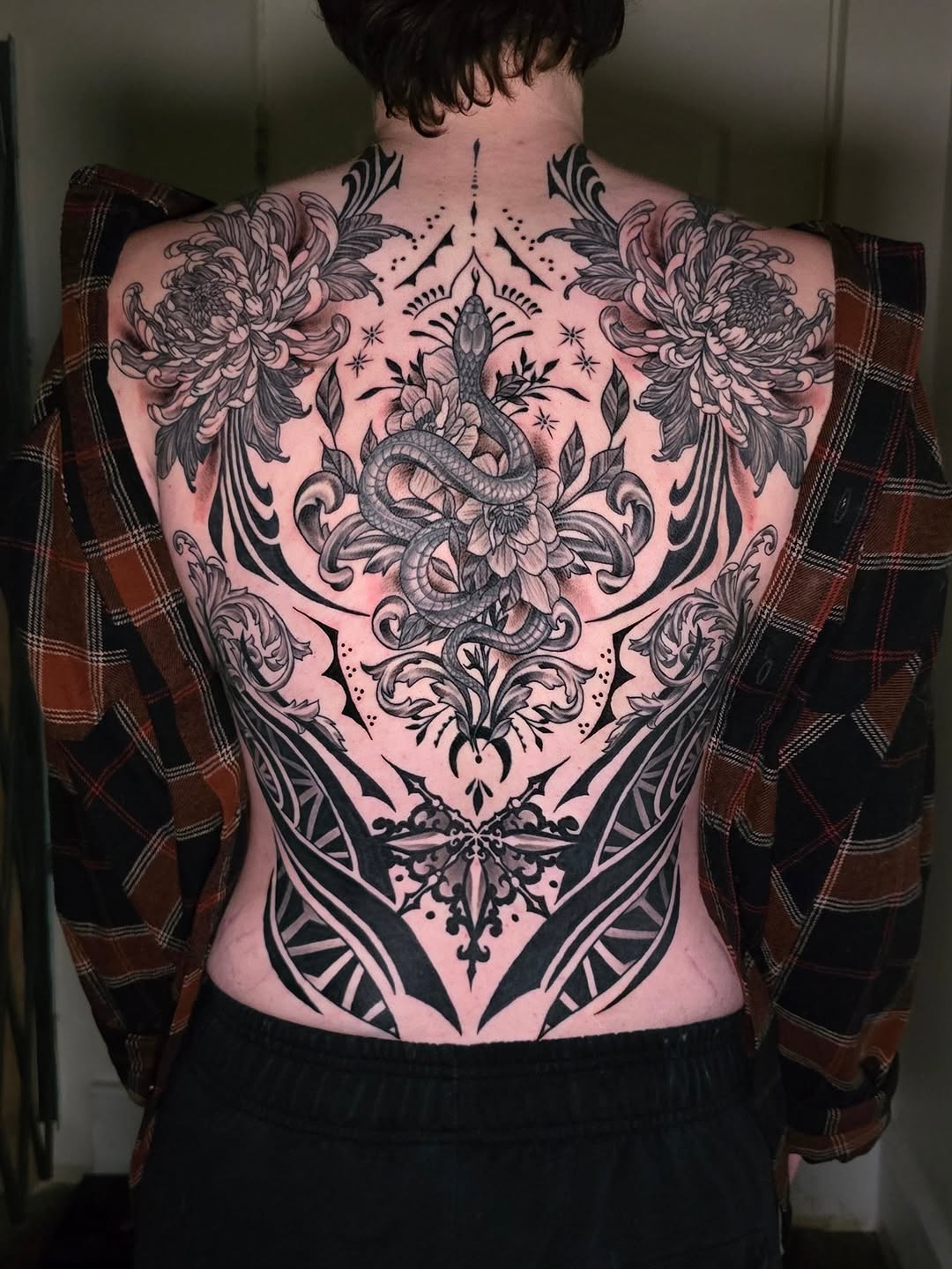Snake and chrysanthemum tribal tattoo on the back by Jack Daniel Knowlden
