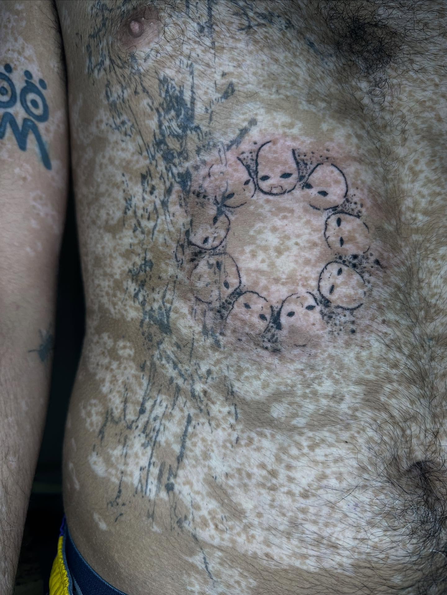 Circle of faces dotwork tattoo on the chest by Swag Originator