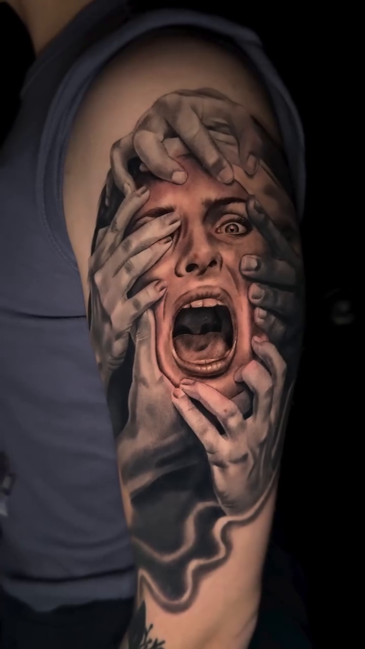 Screaming face with hands covering eyes surrealism tattoo on the upper arm by Kaleb Trujillo