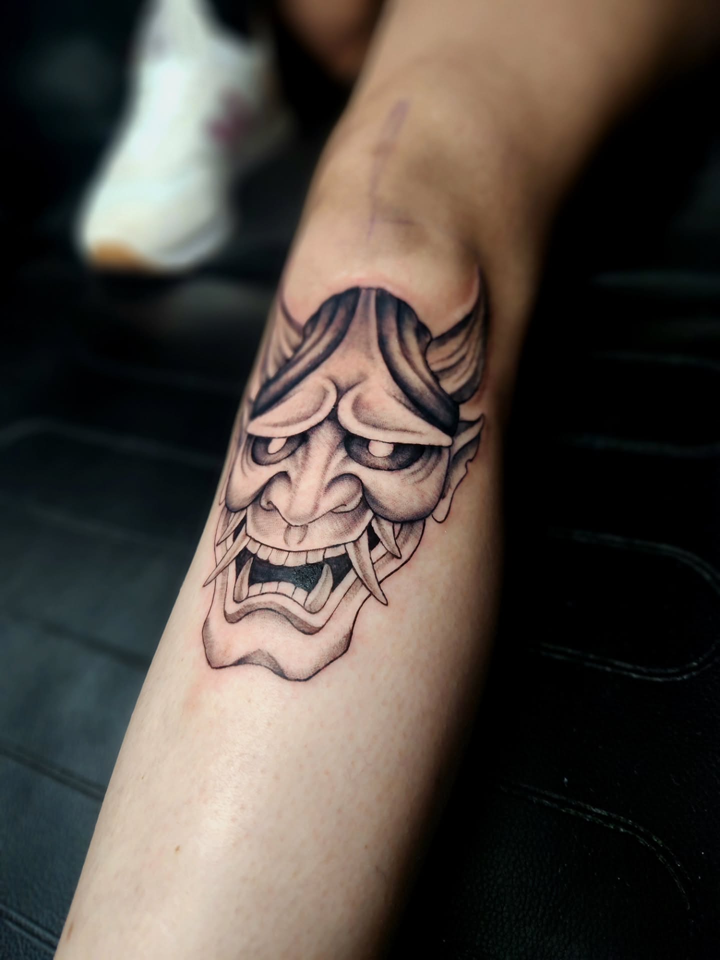Demon mask black and grey tattoo on the forearm by Abby Renteria