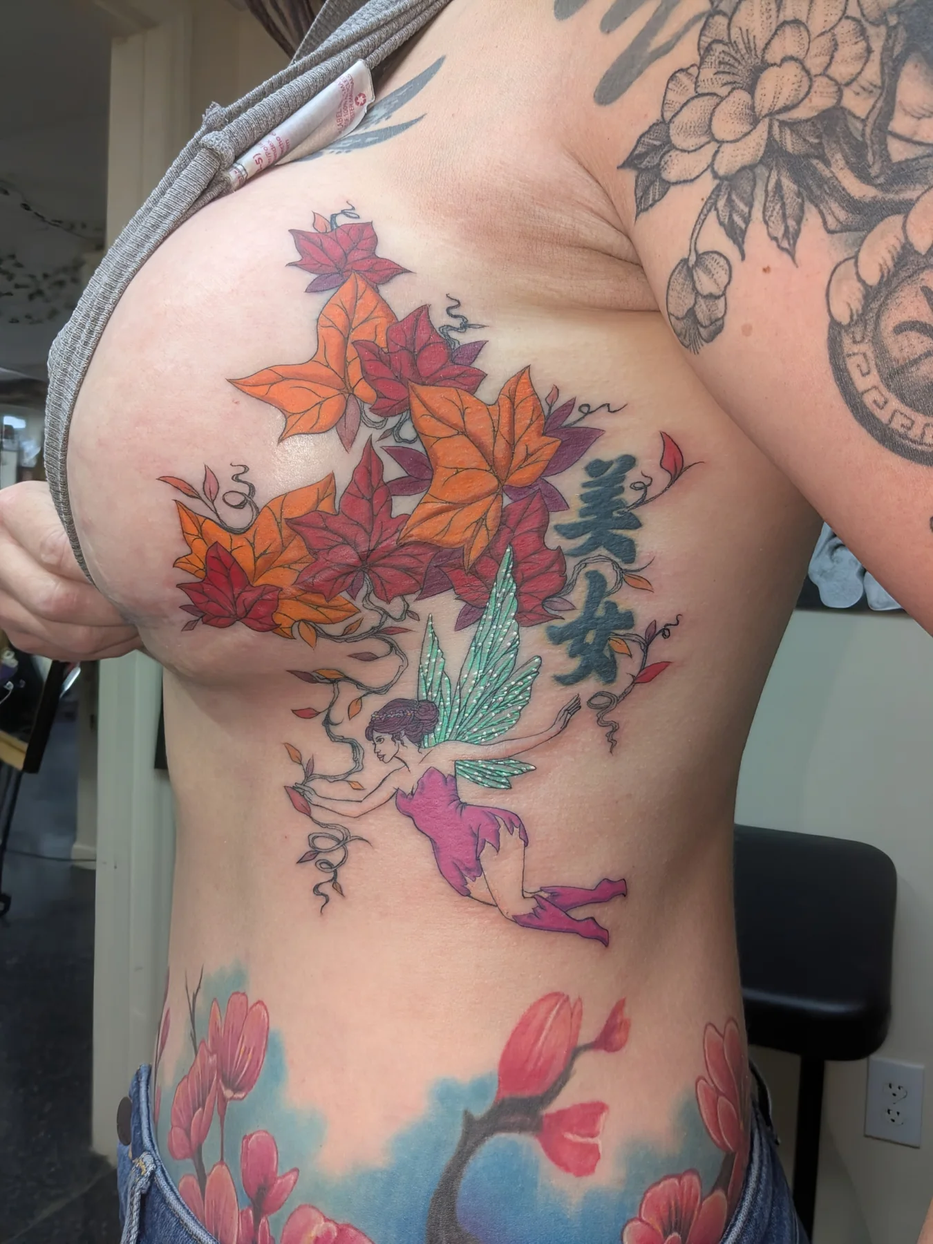 Fairy with autumn leaves new school tattoo on the ribs by Jessica Thomas Fleischman, Morganton, North Carolina