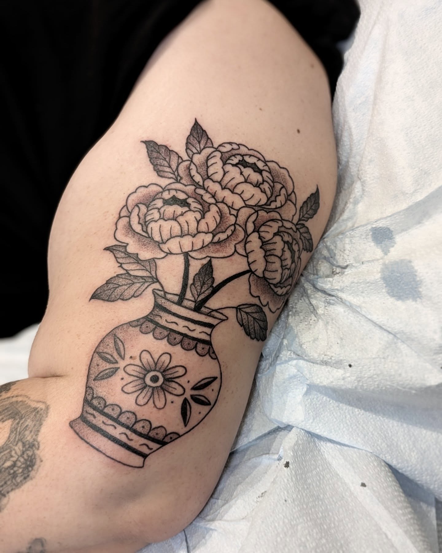 Peony bouquet black and grey tattoo on the upper arm by Dani Harkey