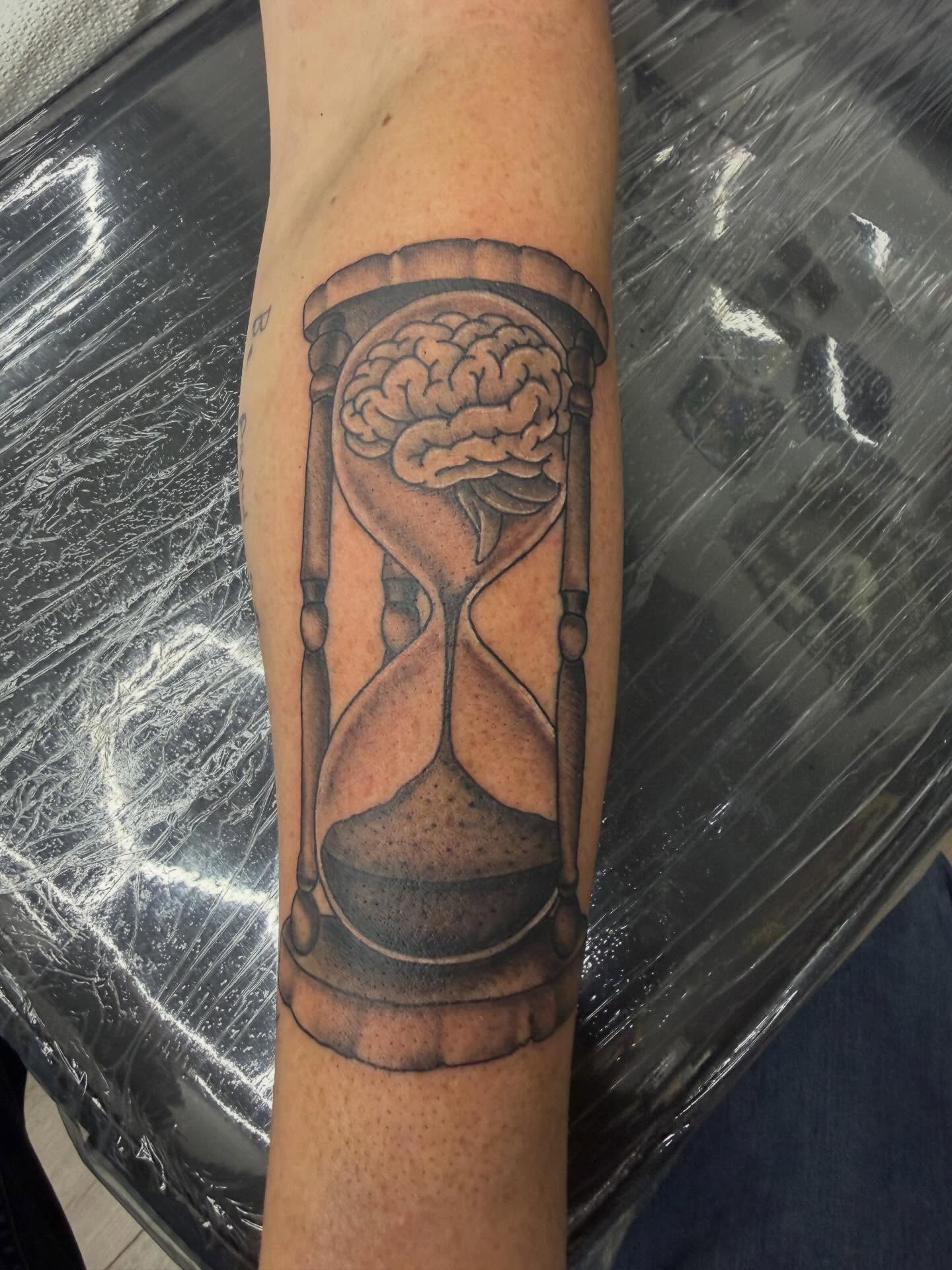 Hourglass with brain black and grey tattoo on the forearm by Matt Hattaway