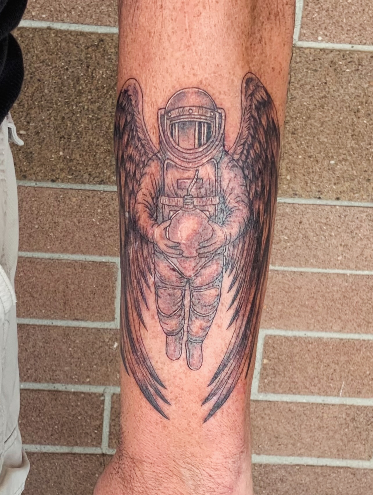 Astronaut with wings realism tattoo on the forearm by QUEEN TATTOO Stephanie Larson