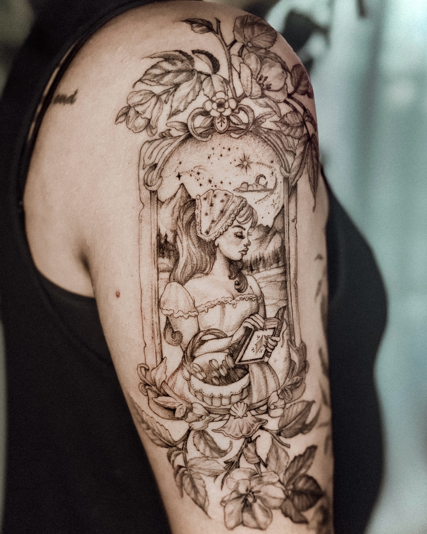 Woman reading realism tattoo on the upper arm by Ayauna Mai