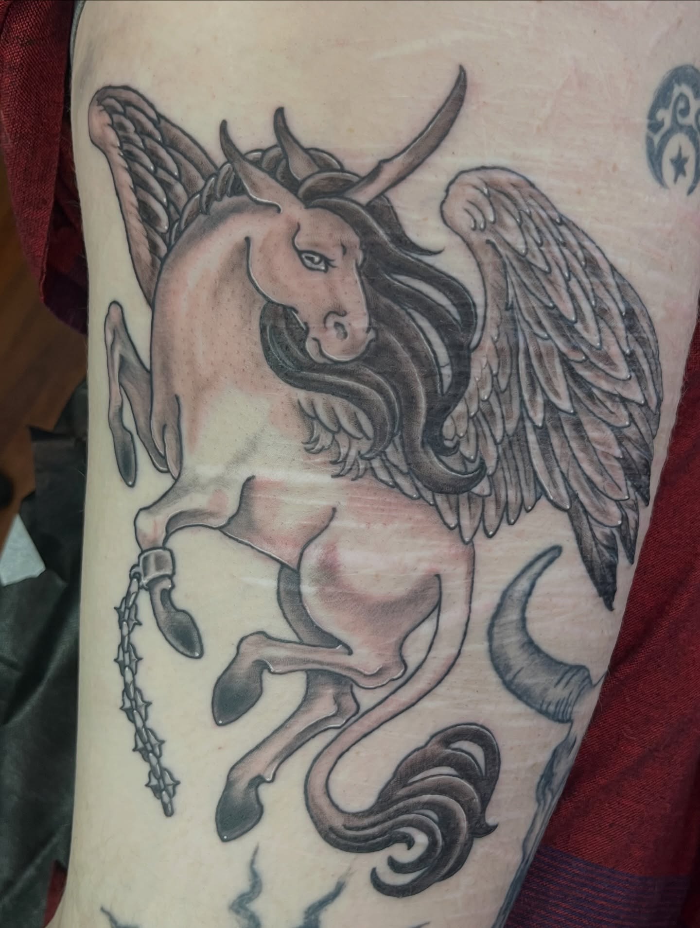 Winged unicorn black and grey tattoo on the forearm by Caito Conner