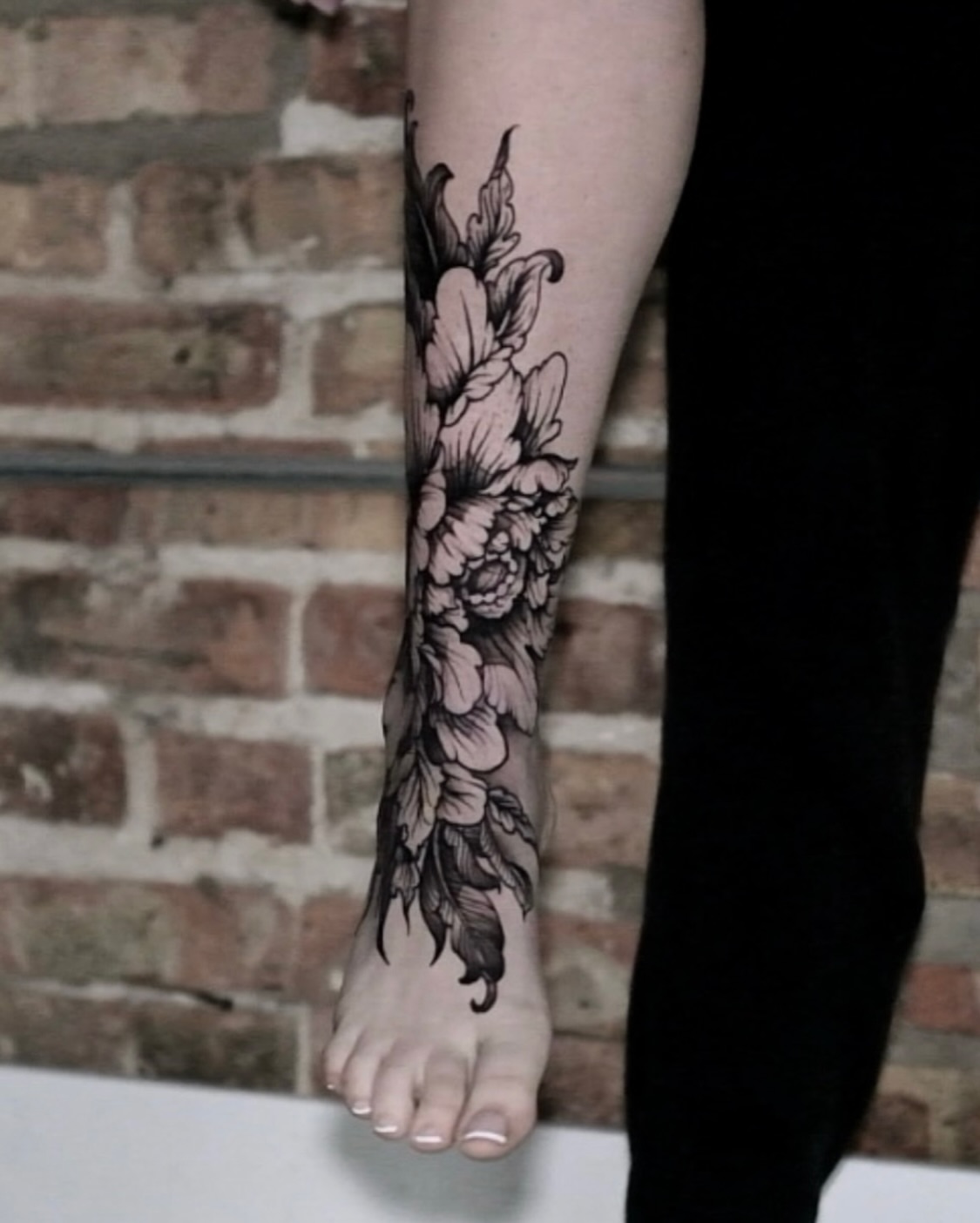 Floral bouquet black and grey tattoo on the calf by Macayla Myers