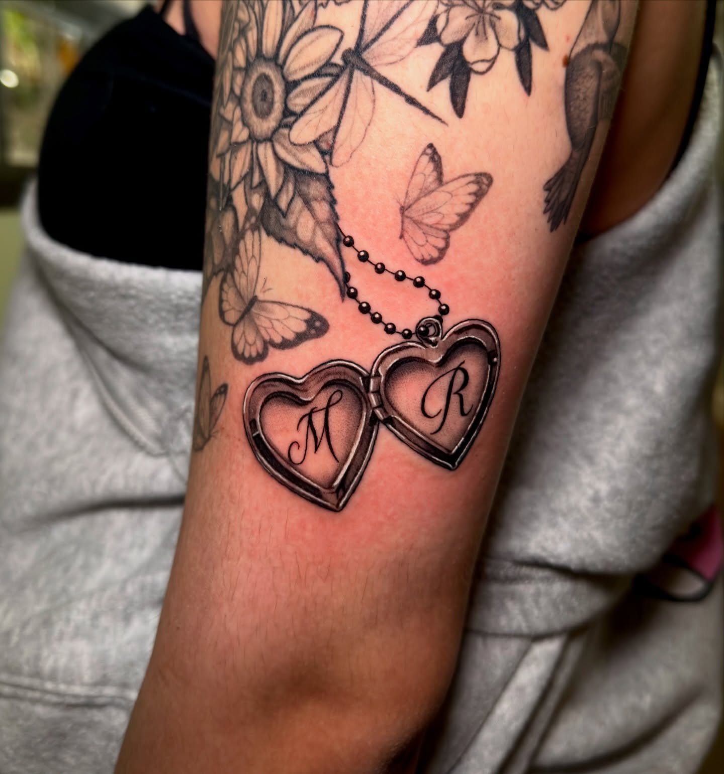 Heart locket black and grey tattoo on the forearm by Marisa Biddle