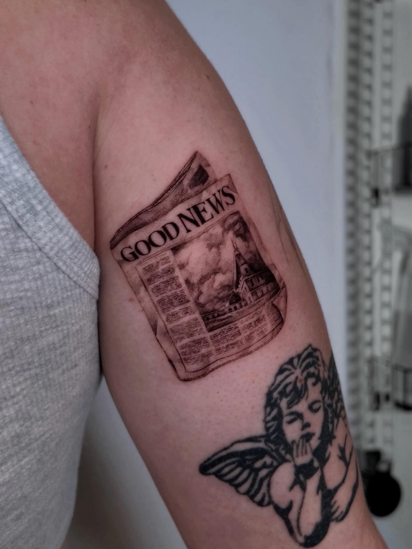 Newspaper and angel black and grey tattoo on the forearm by Gabriel