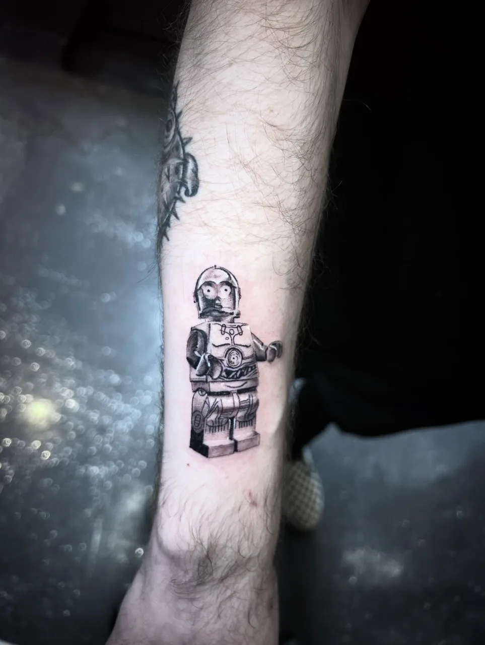 Robot black and grey tattoo on the forearm by Dylan Stevens