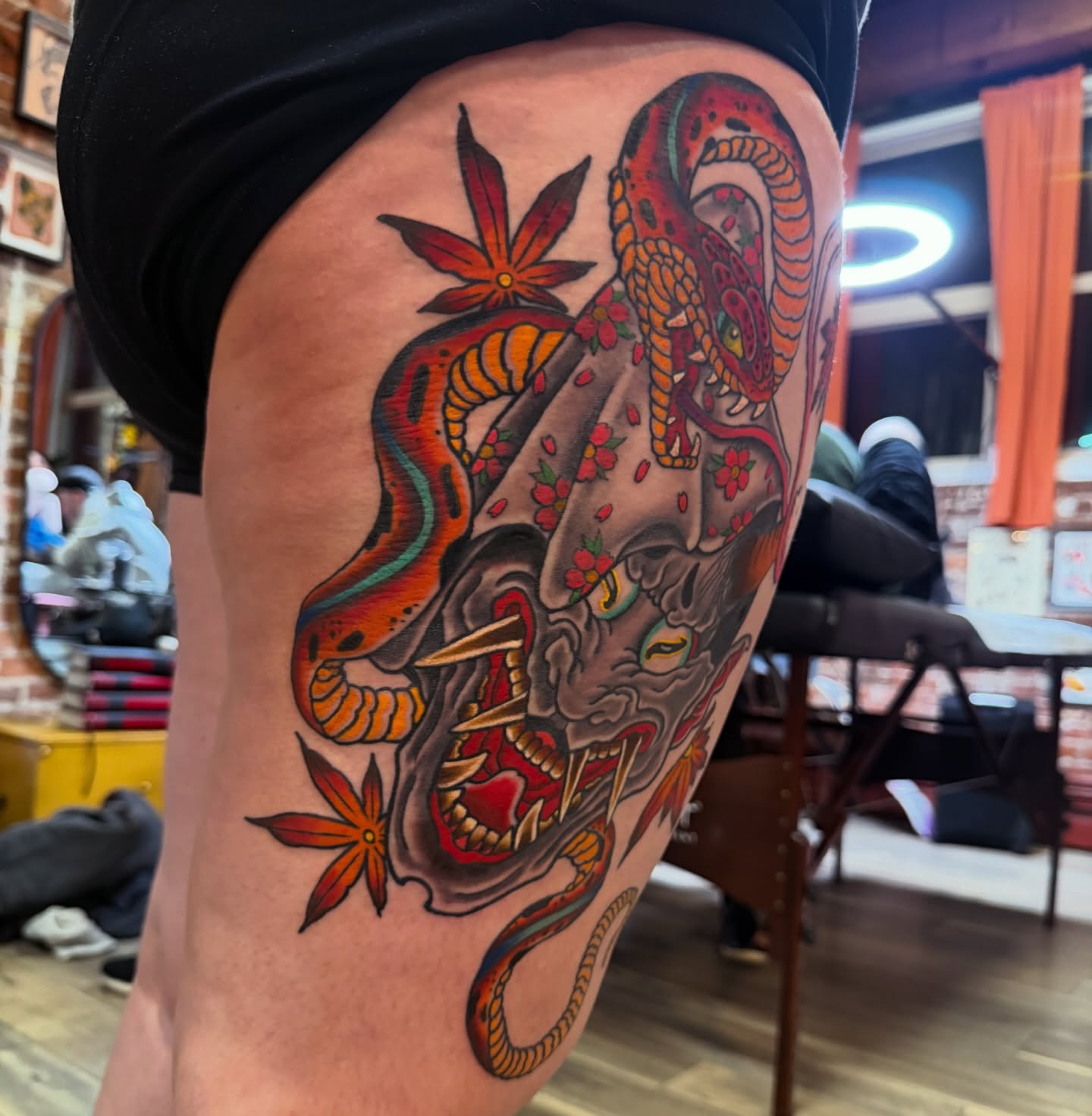 Snake and skull American traditional tattoo on the thigh by Trevor Berry
