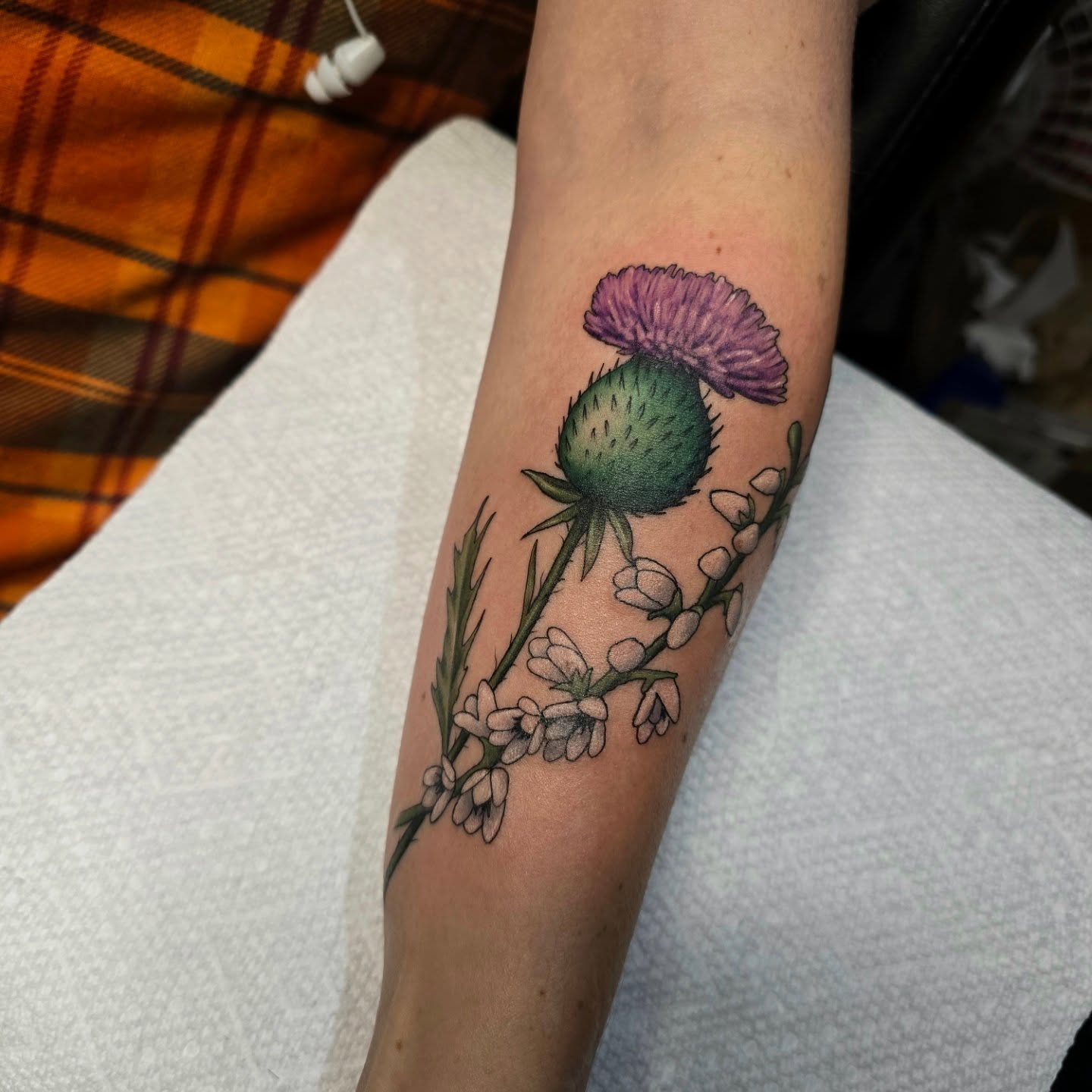 Thistle and flowers realism tattoo on the forearm by Gabrielle Nicole Soucie