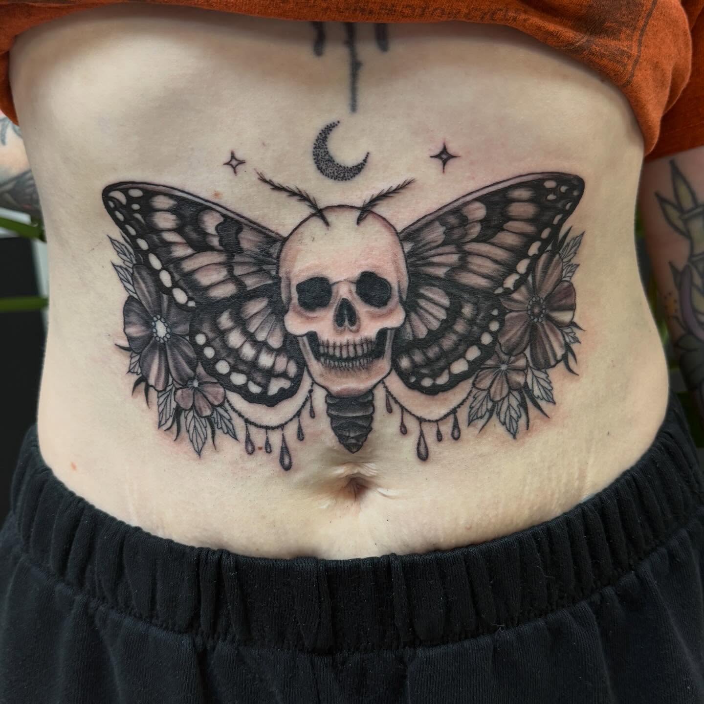 Skull with butterfly wings dark realism tattoo on the torso by Aura Noire