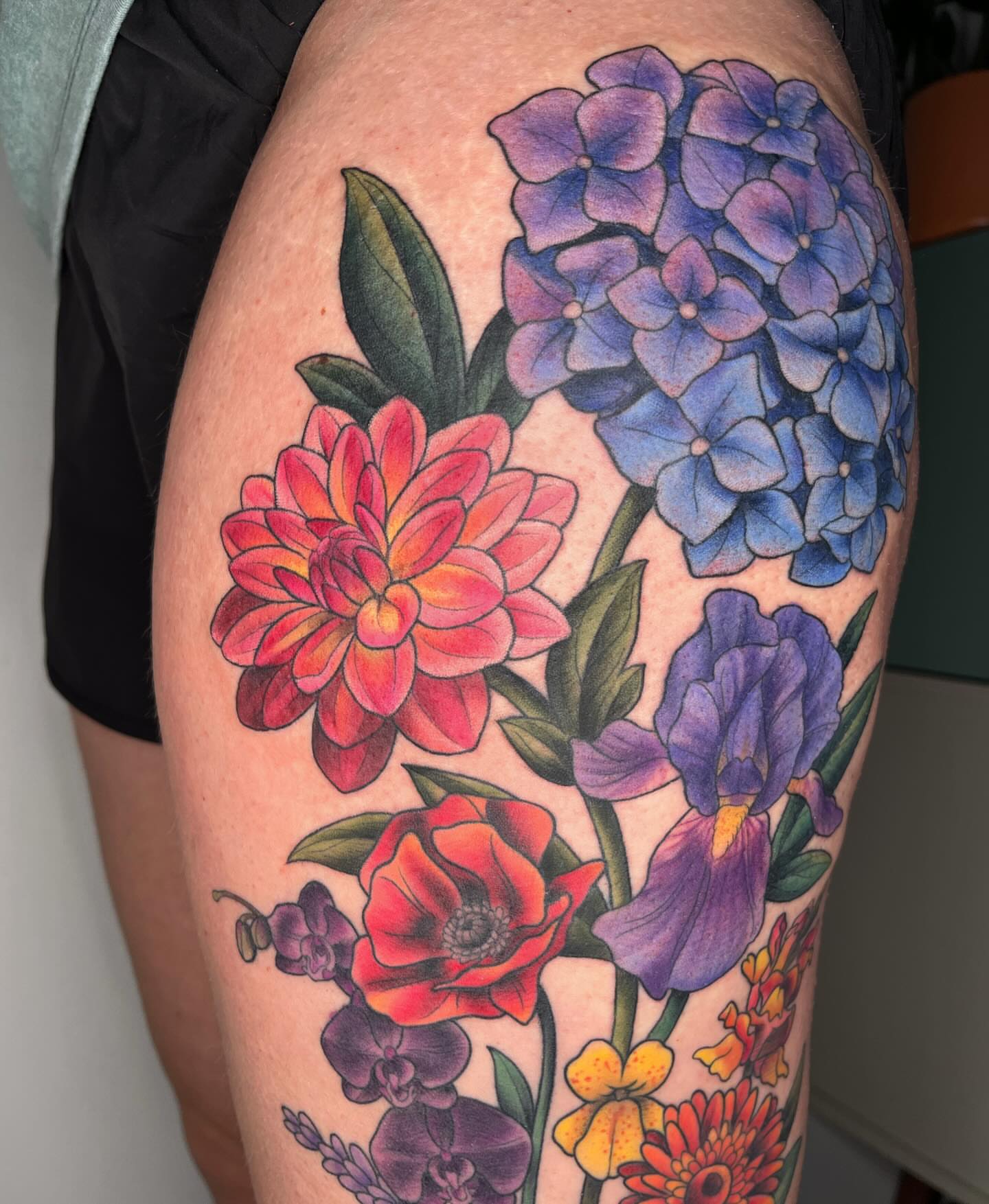 Floral bouquet realism tattoo on the thigh by Emi Collison