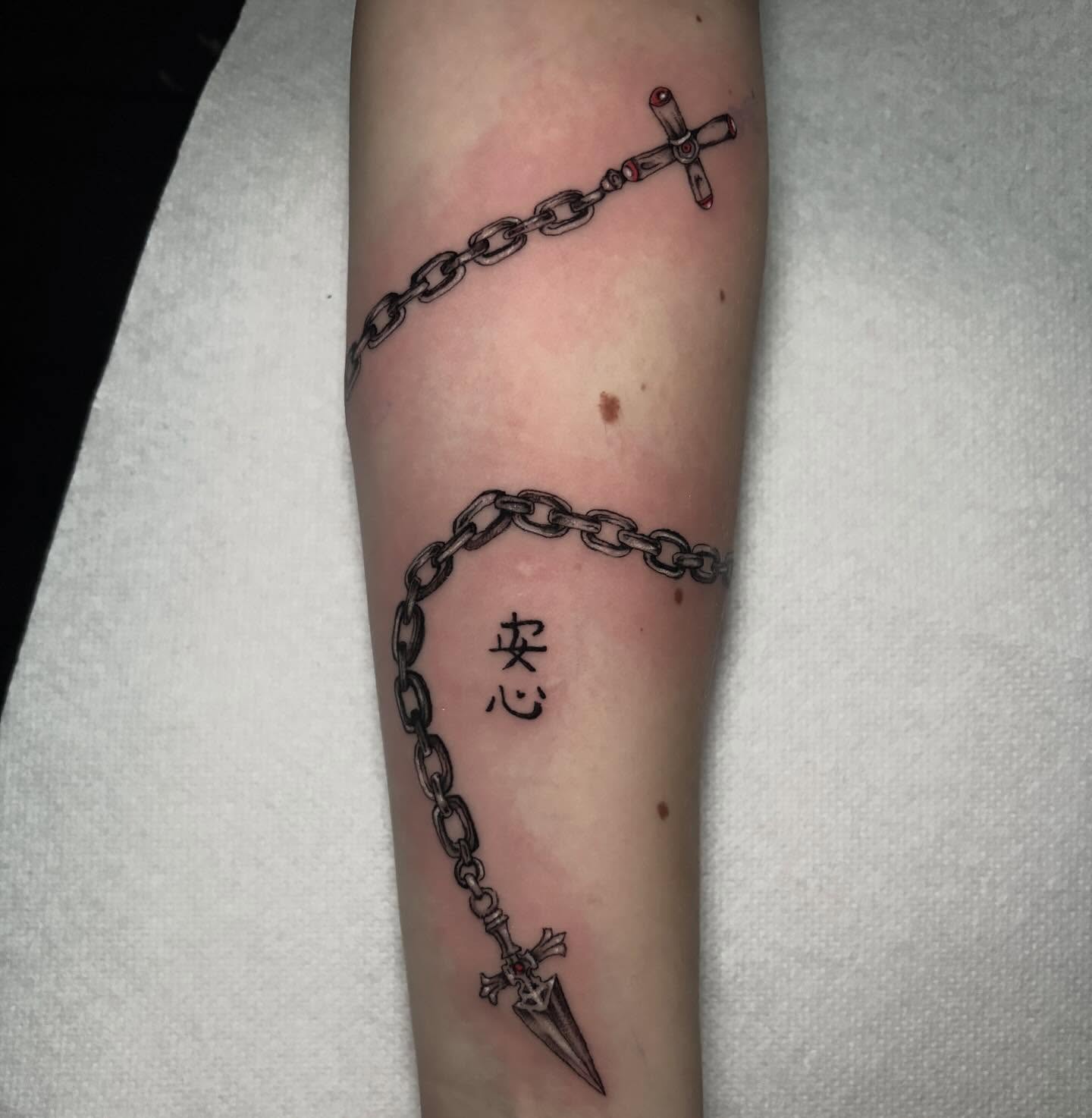 Chain and dagger black and grey tattoo on the forearm by Ashley Denise