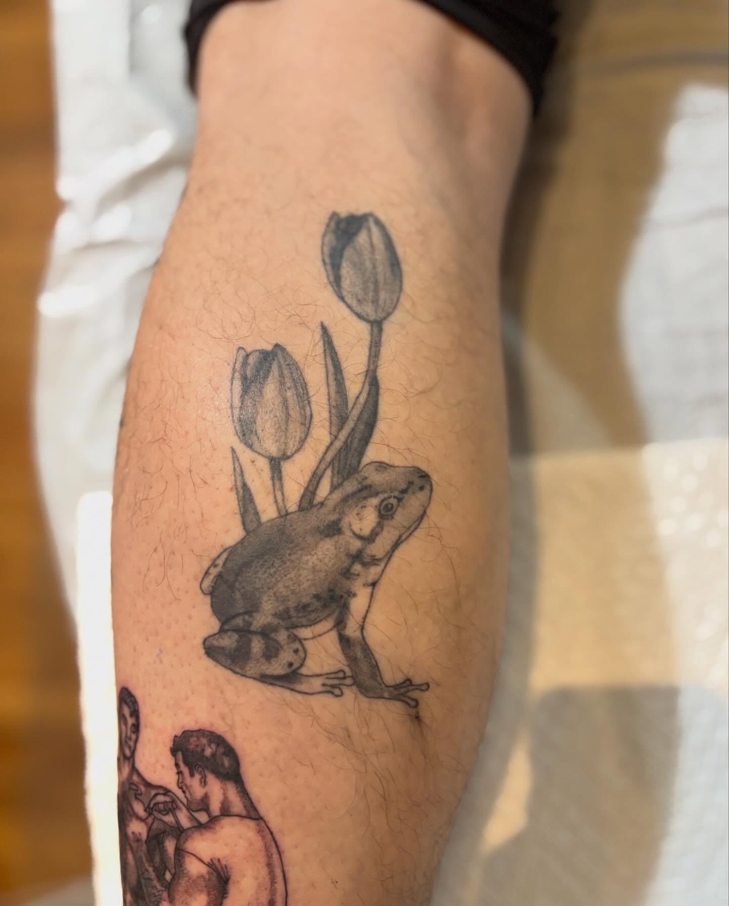 Frog and tulips black and grey tattoo on the forearm by Dylan Coverdale
