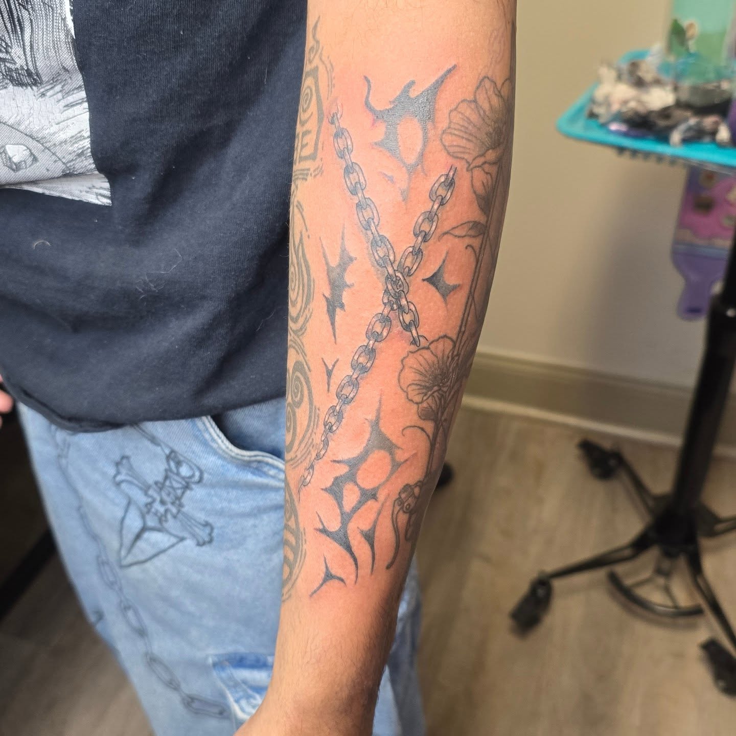 Chain and floral black and grey tattoo on the forearm by Val Sanchez
