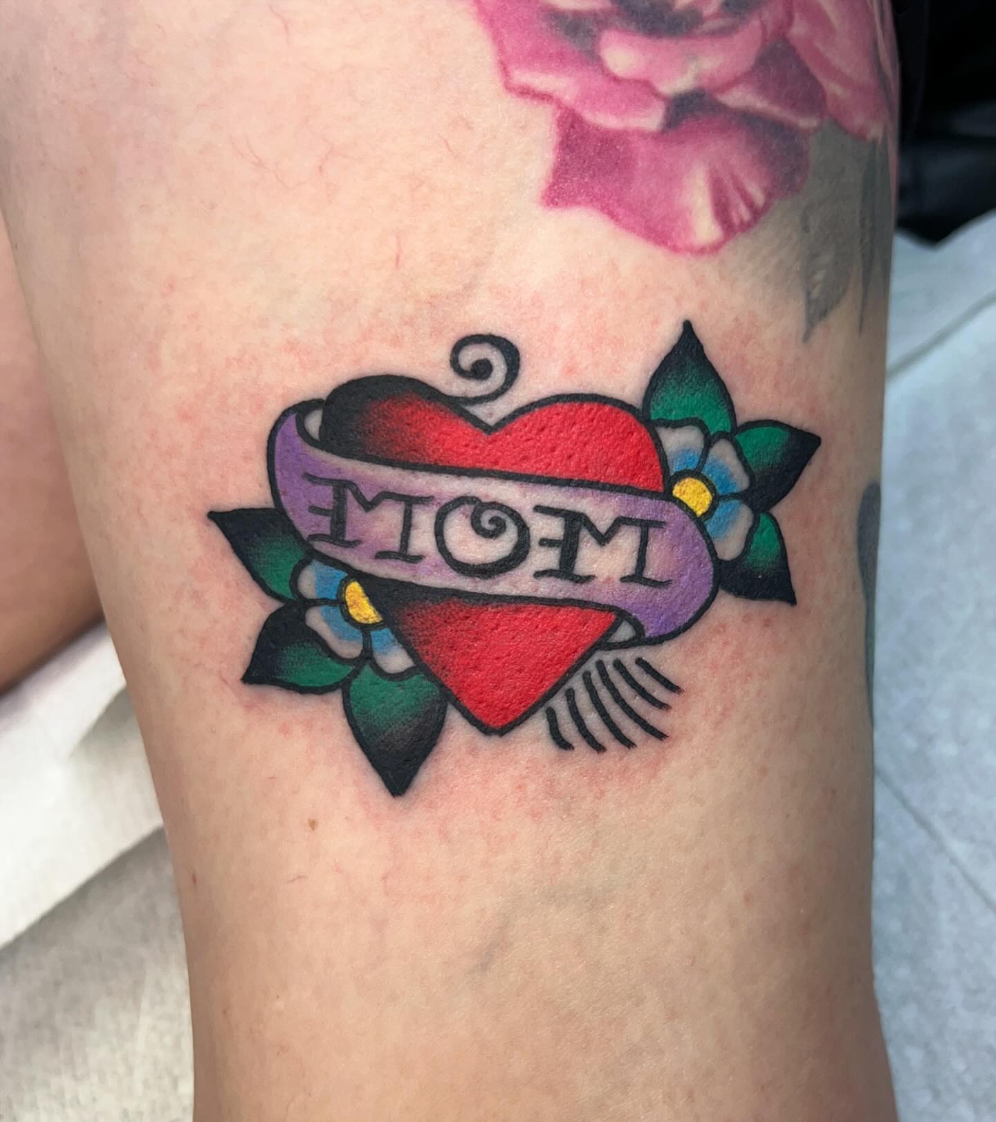 Heart with 'mom' banner American traditional tattoo on the forearm by Tattoo