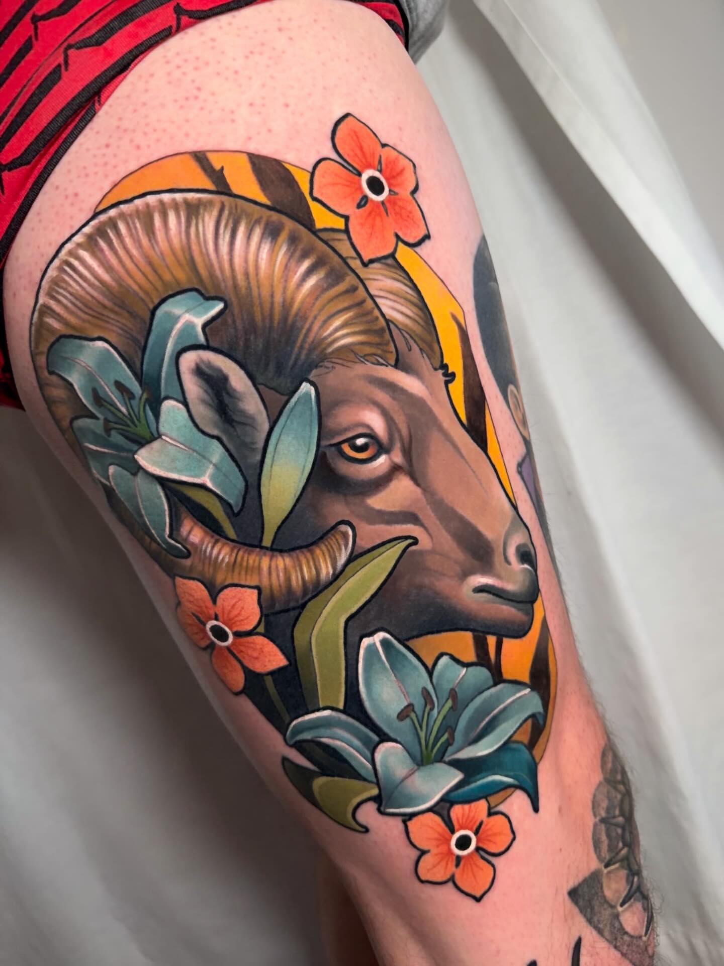 Ram head with flowers American traditional tattoo on the thigh by Milo Alfring Tattoo
