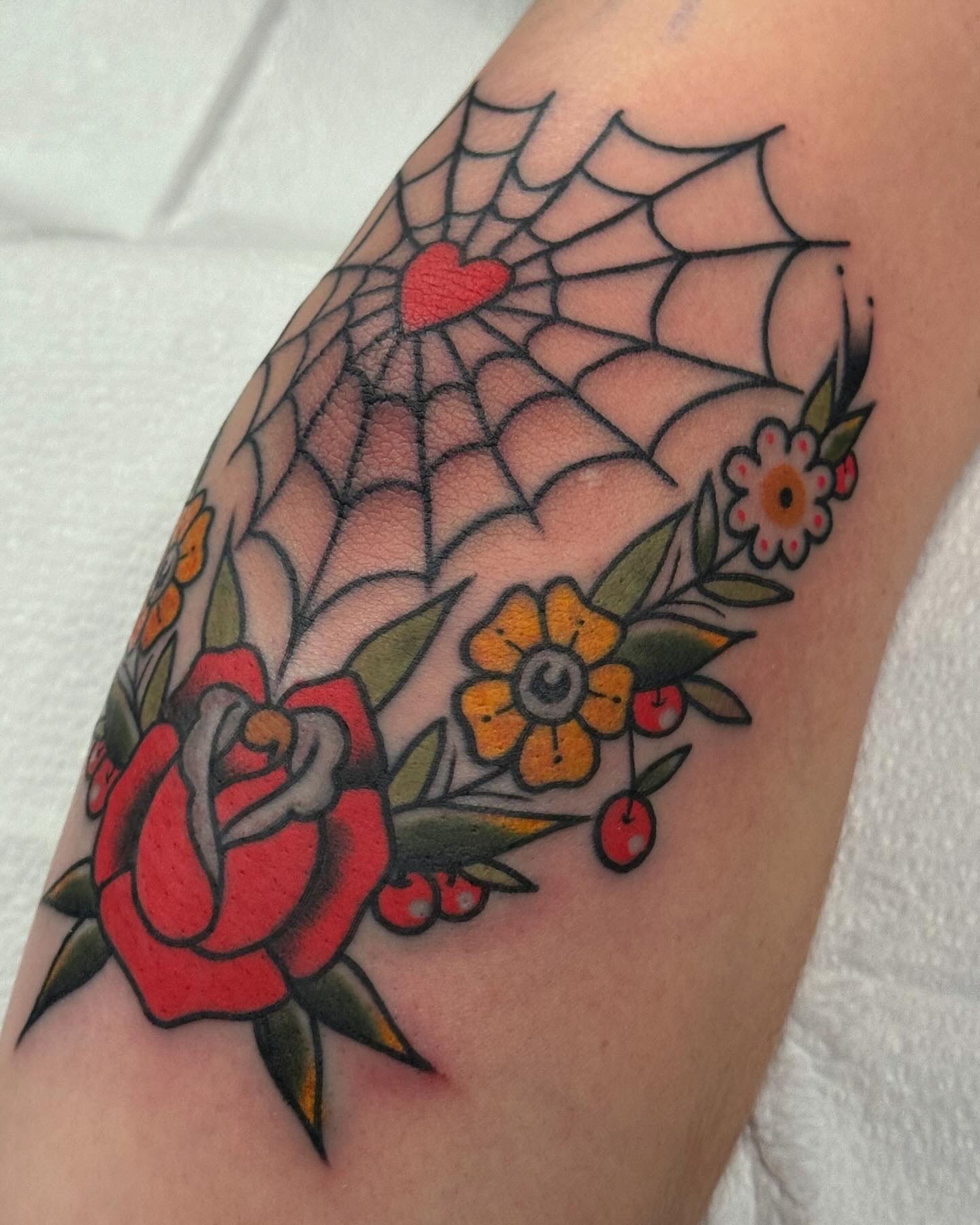 Spiderweb and flowers American traditional tattoo on the forearm by Cory Craft
