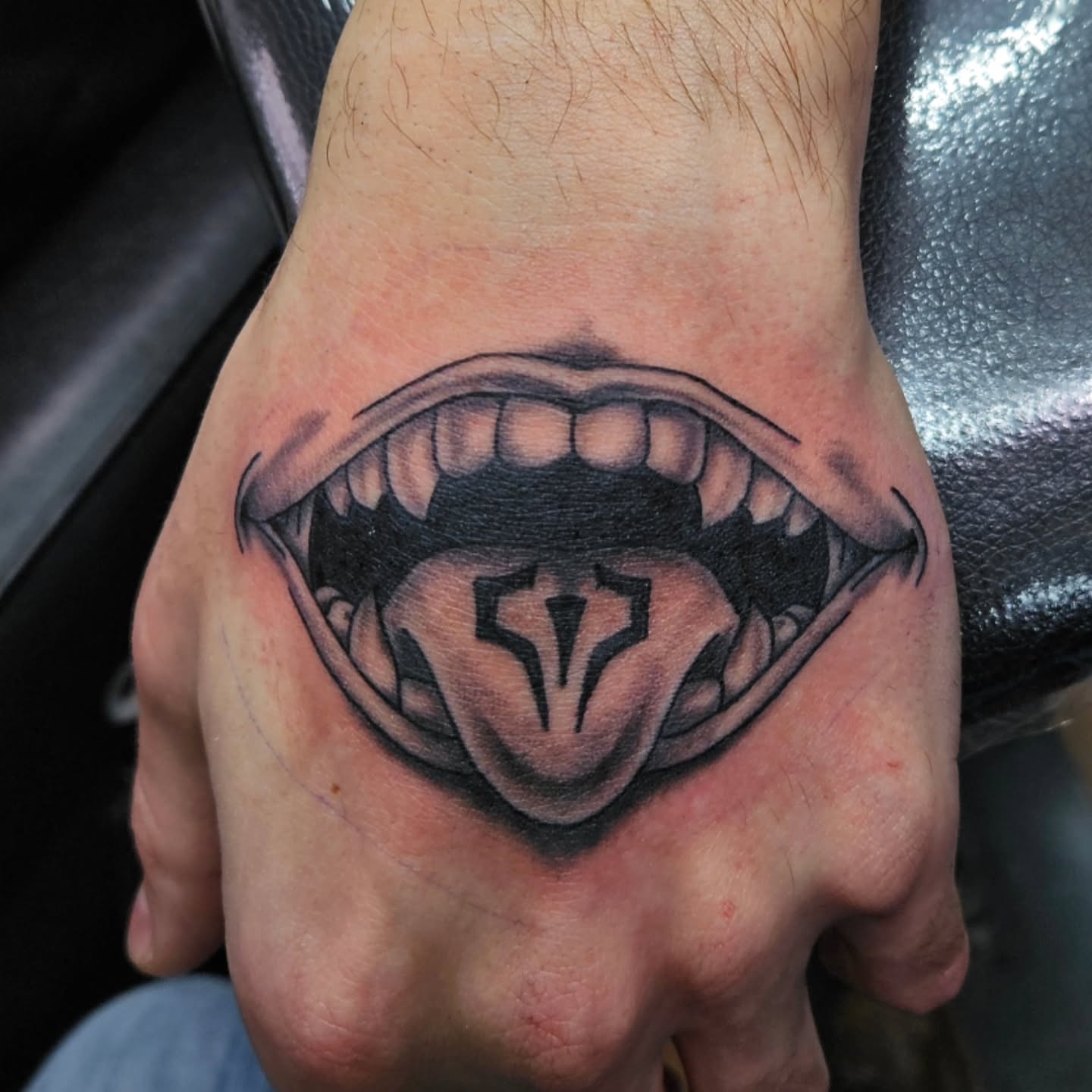 Fangs and tongue black and grey tattoo on the hand by Danny