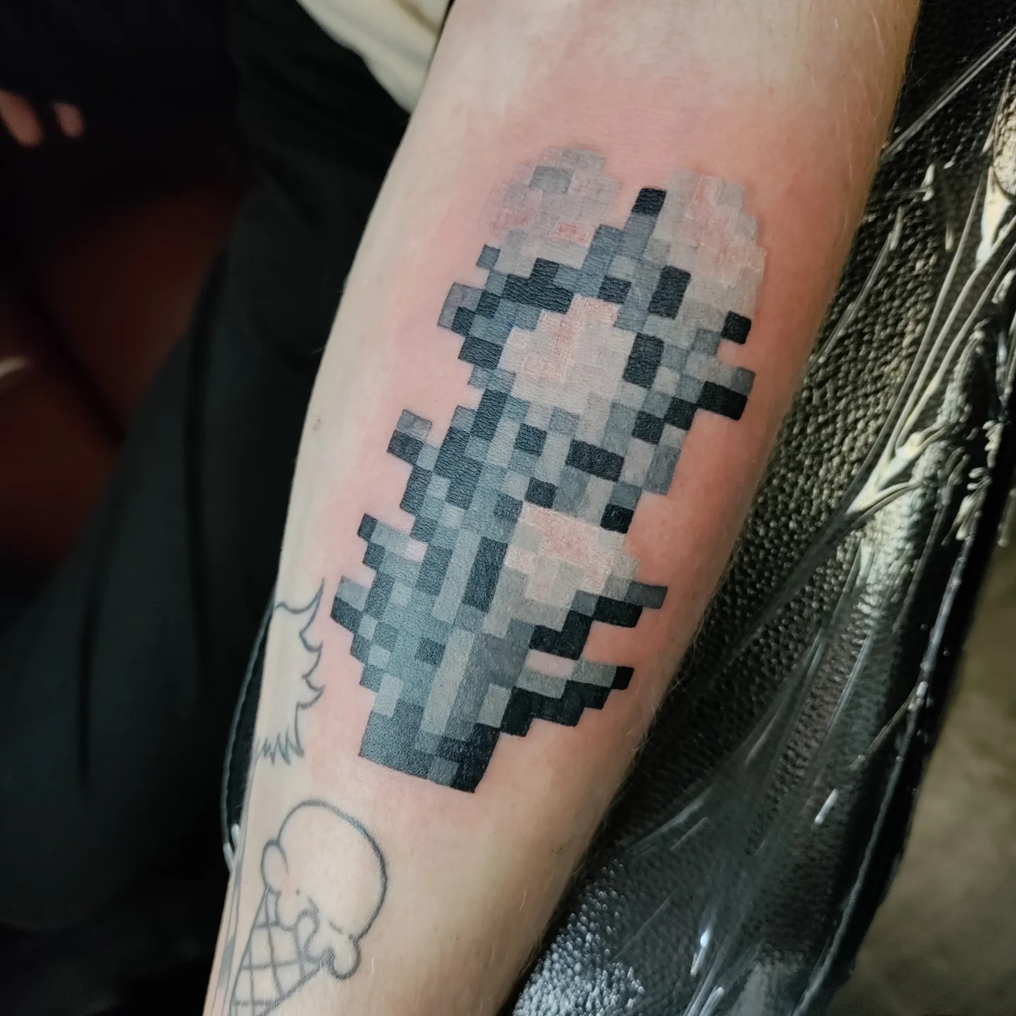 Pixelated character dotwork tattoo on the forearm by Kennedy Jones, Lee's Summit, Missouri