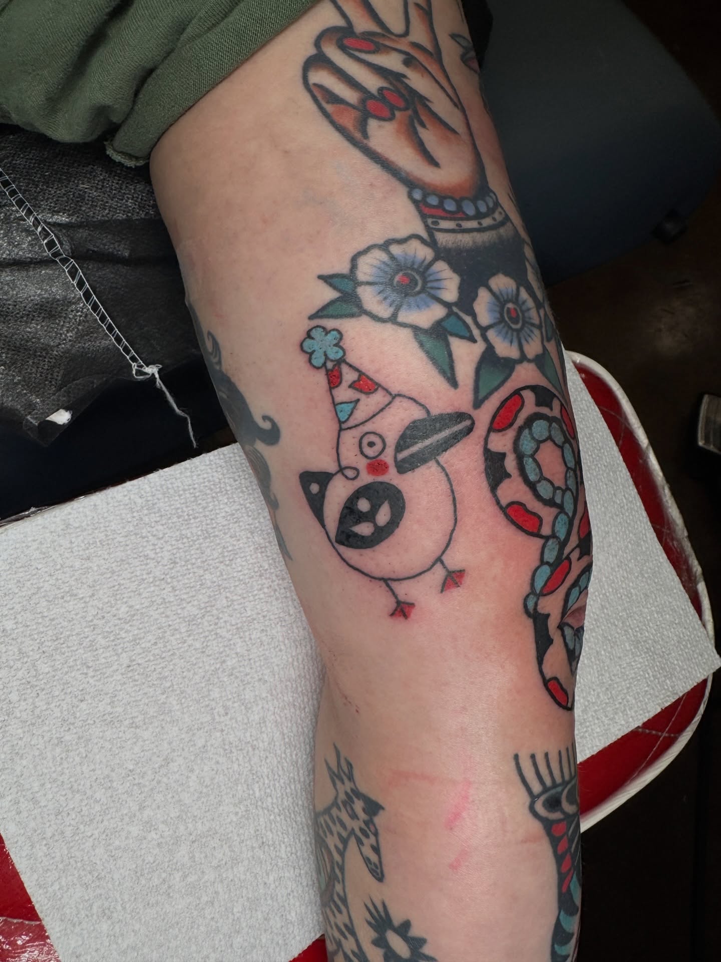 Bird with party hat American traditional tattoo on the forearm by lily gustave i tattoo