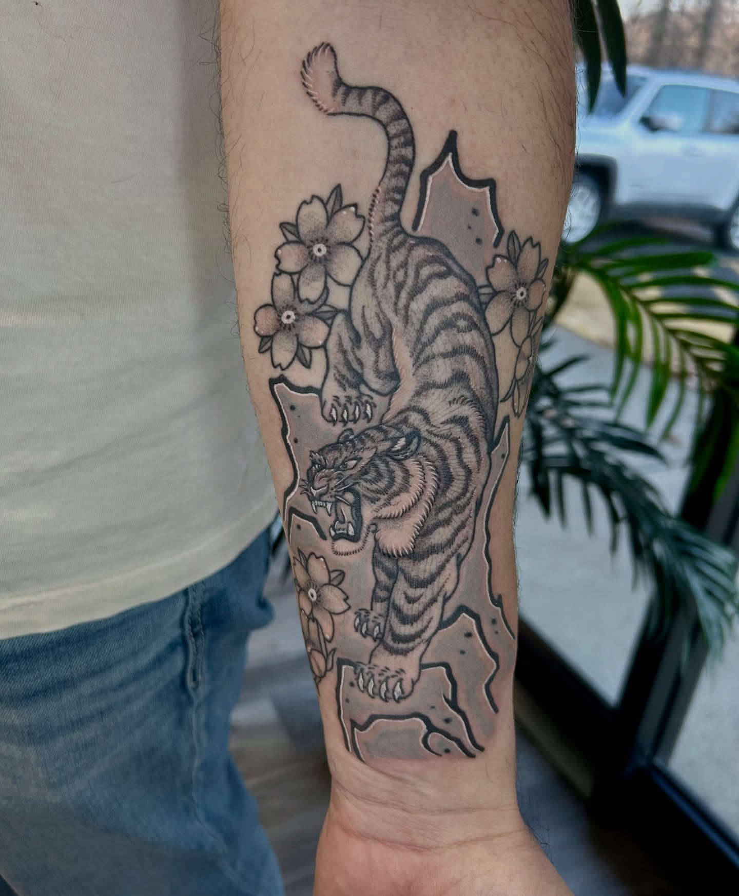 Tiger and flowers black and grey tattoo on the forearm by Taylor Heidtbrink