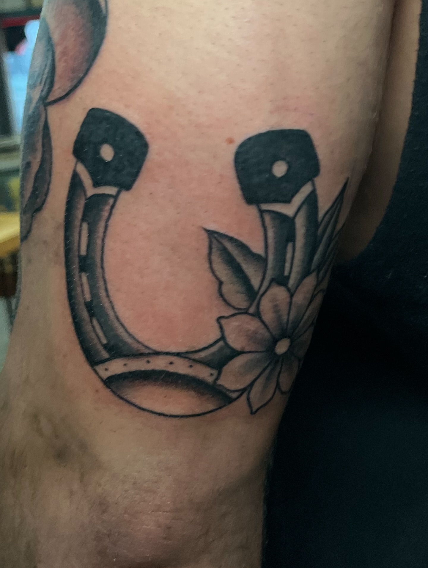 Horseshoe and flower black and grey tattoo on the forearm by Ashley Camp