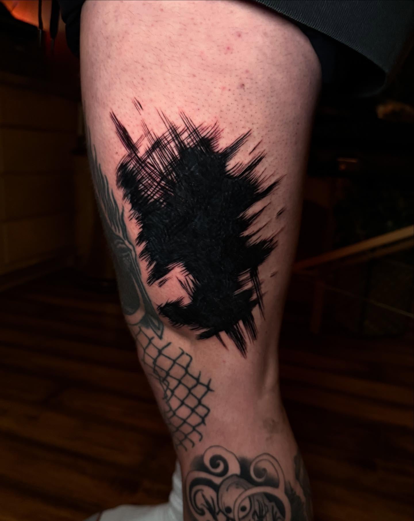 Abstract splatter black and grey tattoo on the thigh by Emily Lestrange
