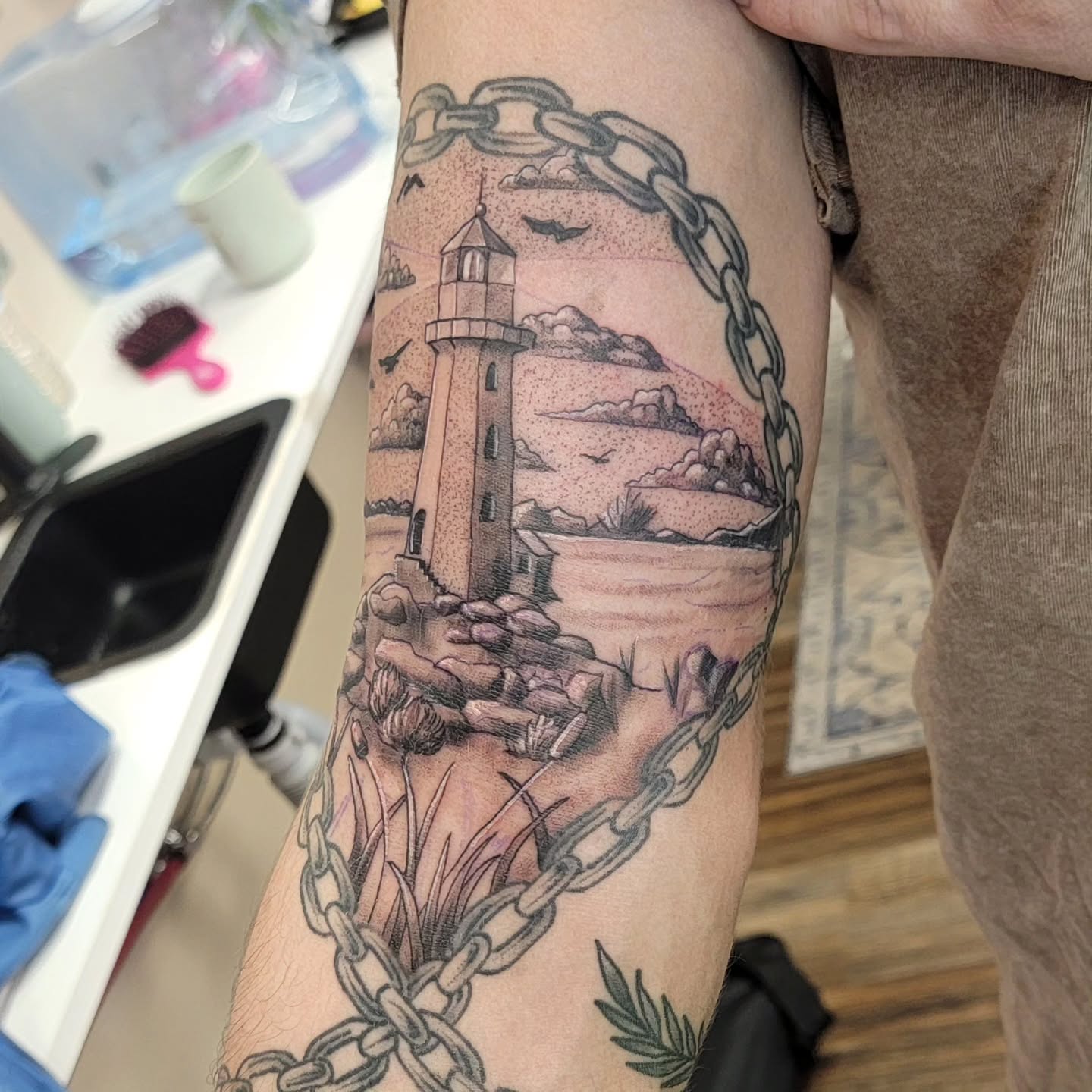 Lighthouse and chains minimalist tattoo on the forearm by Hatchetfoot Art
