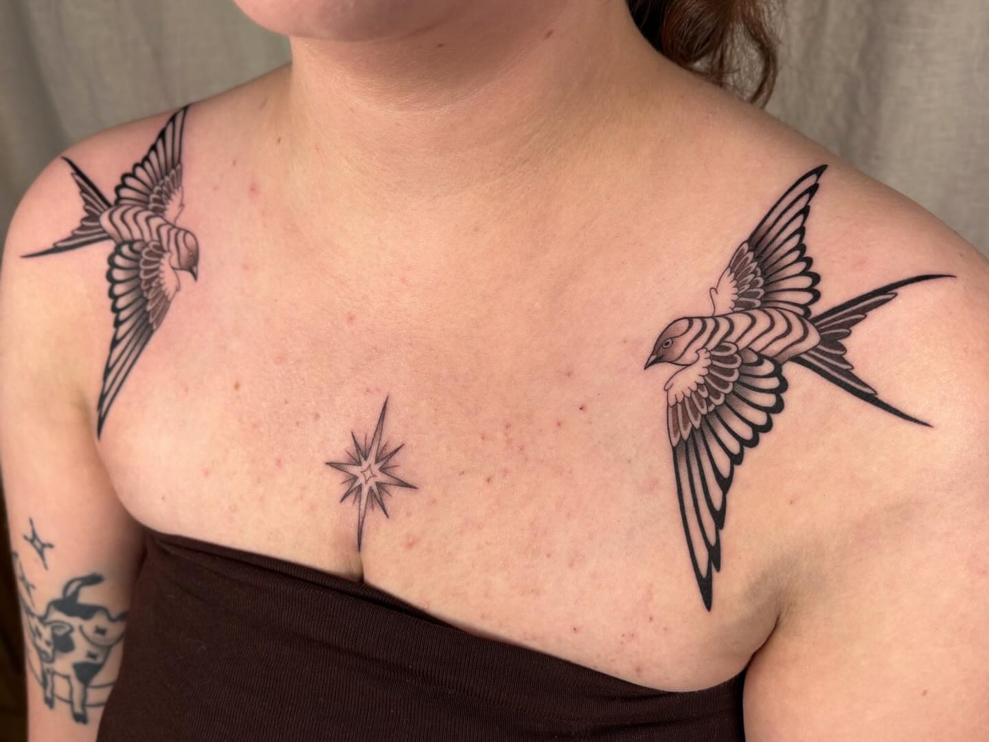 Swallows and star black and grey tattoo on the chest by Anna Sage