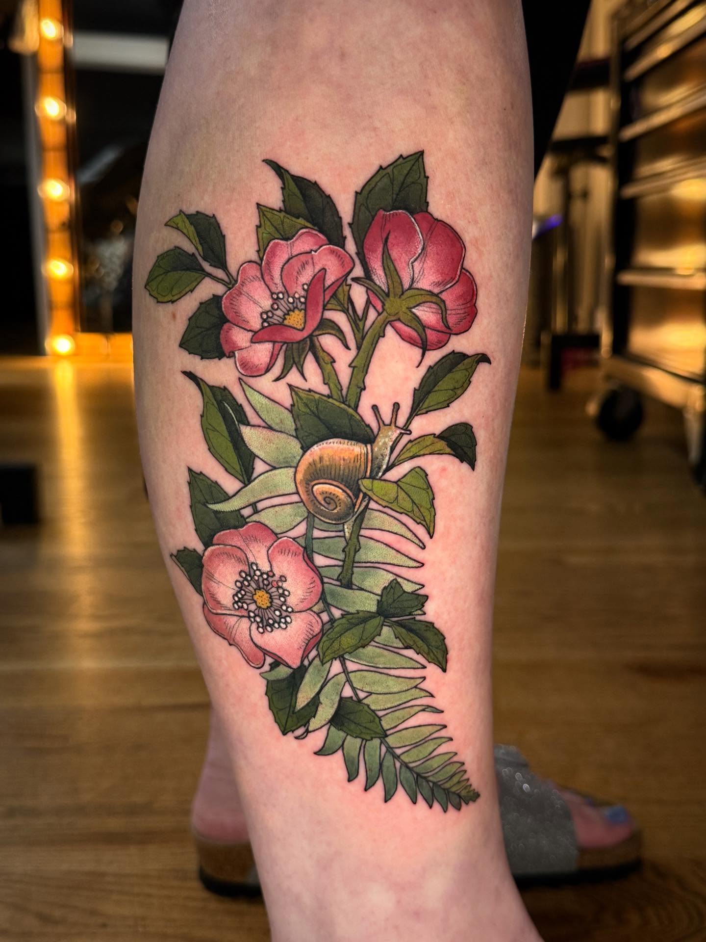 Flowers and snail realism tattoo on the calf by Katy Bisby