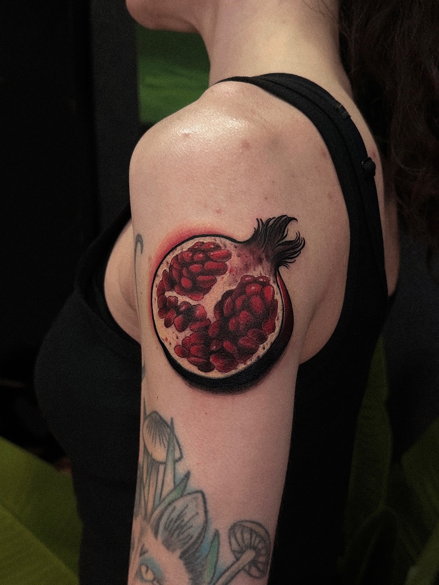 Pomegranate realism tattoo on the upper arm by Tattoo Artist 👩🏻‍🎨 ATX