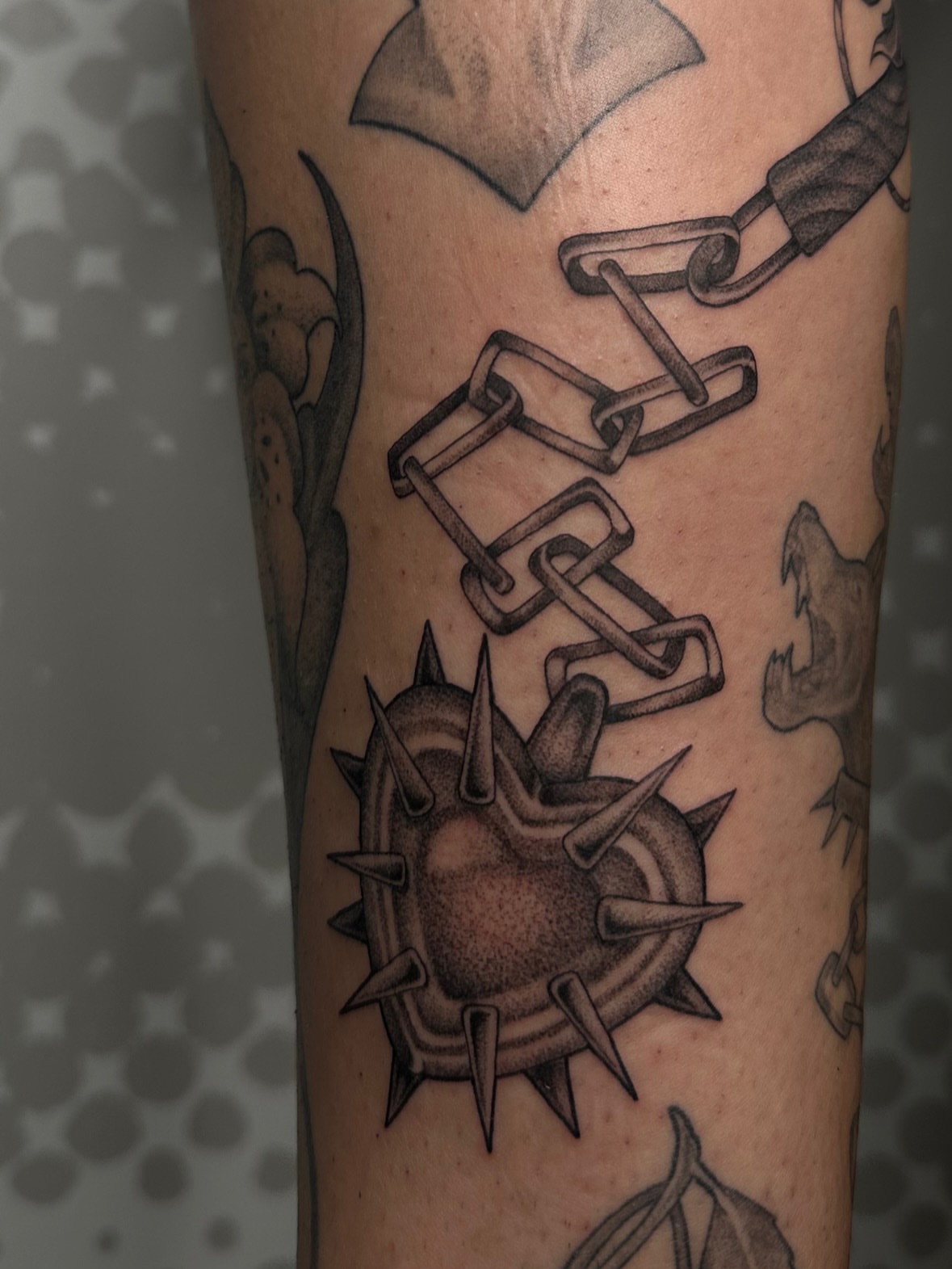 Spiked heart with chains black and grey tattoo on the forearm by Hannah Burnside, Charlotte, North Carolina