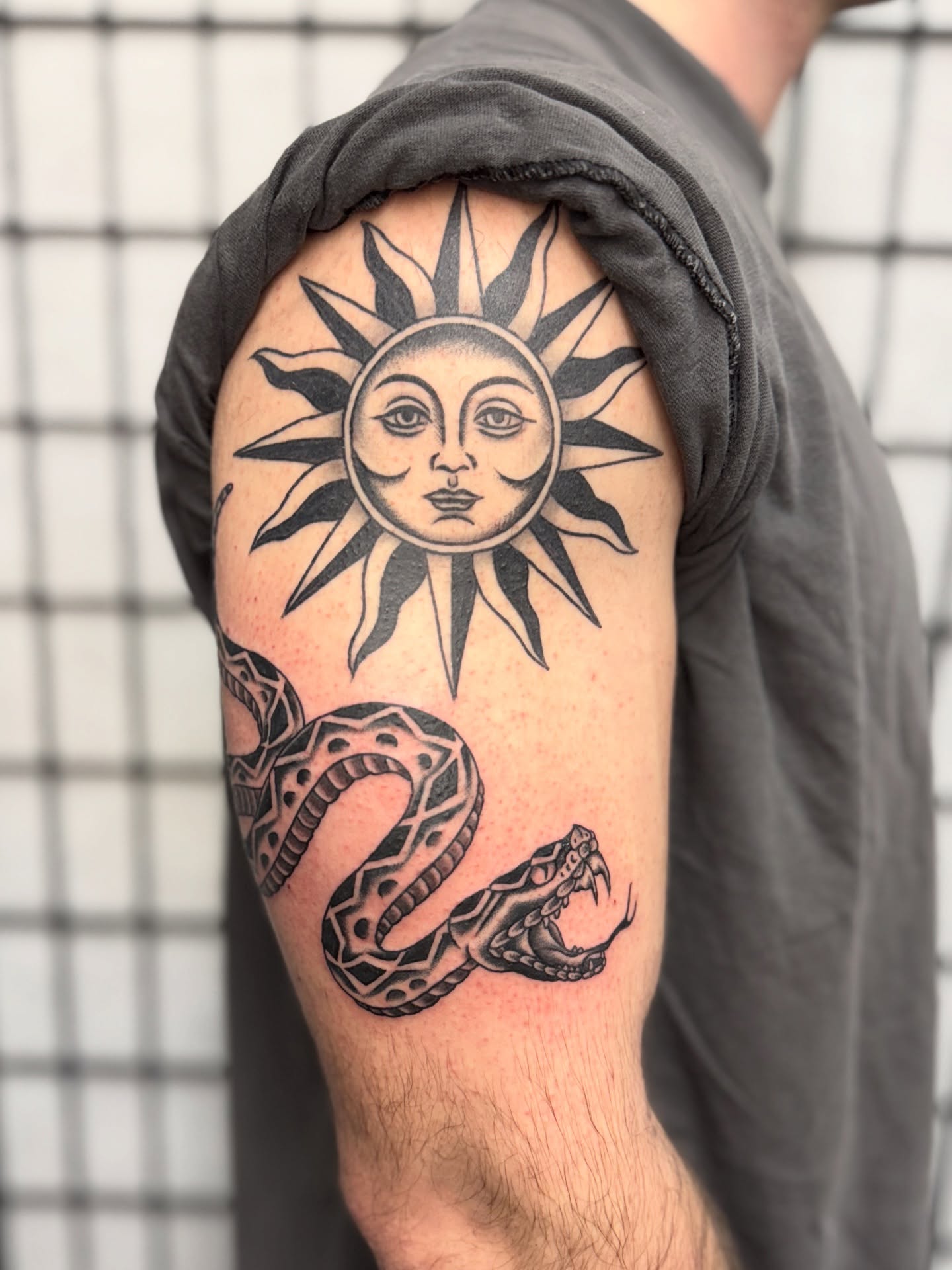 Sun and snake geometric tattoo on the shoulder by Sarah Pham