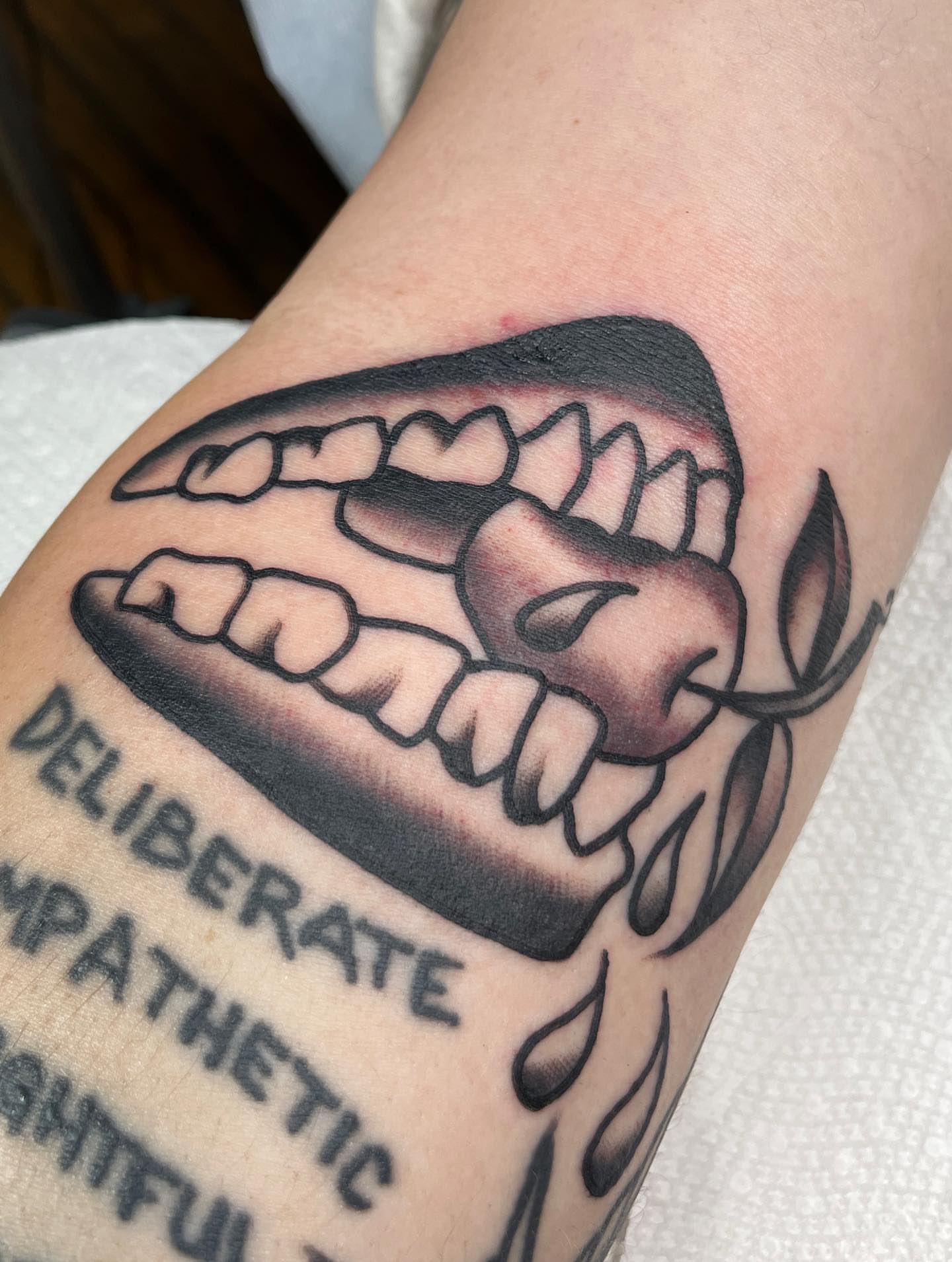 Teeth and heart black and grey tattoo on the forearm by Charlie Ostrom, Durham, North Carolina