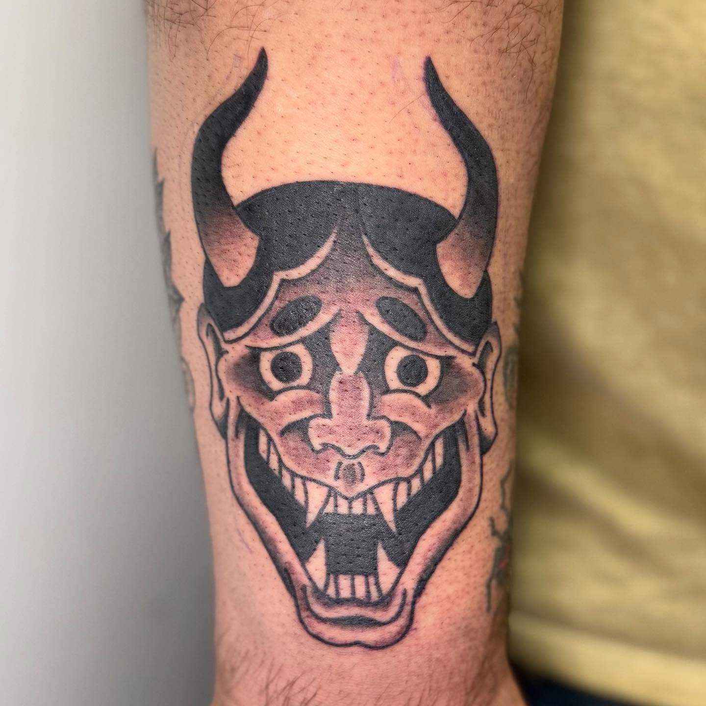 Demon mask black and grey tattoo on the forearm by Rigo Vargas