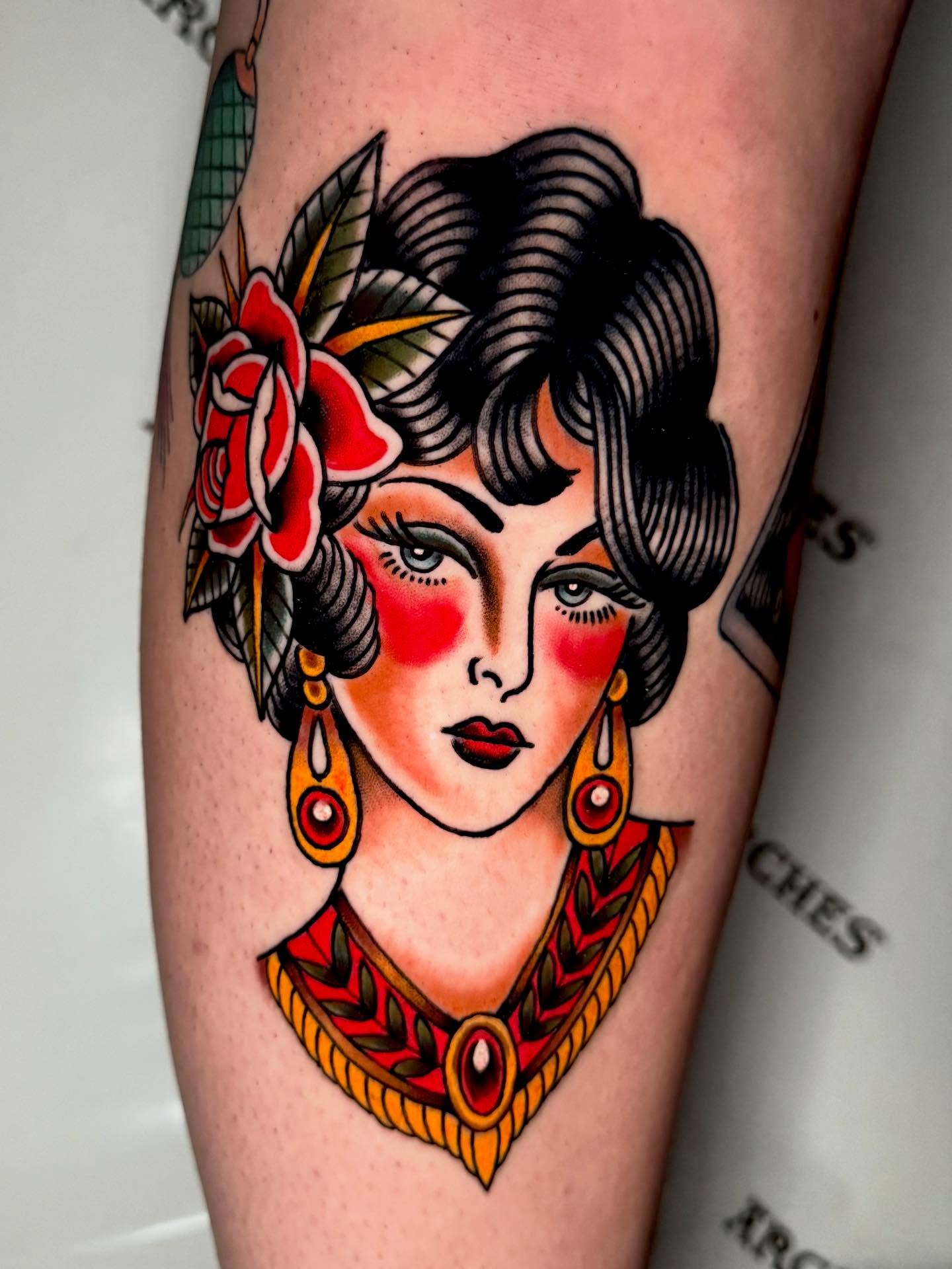 Woman with floral headdress American traditional tattoo on the forearm by Seth Walker