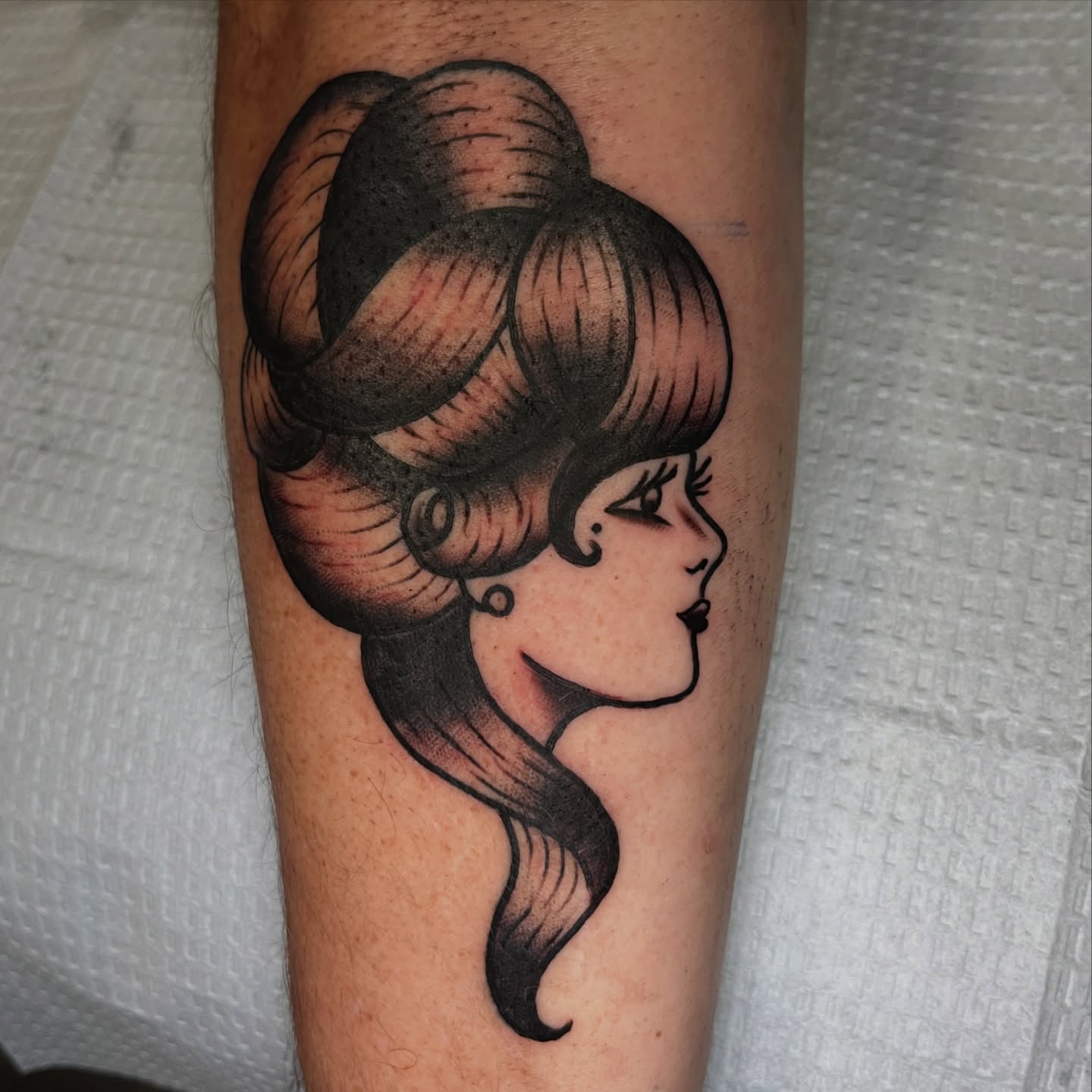 Woman with large hairstyle black and grey tattoo on the forearm by Ryan Kim