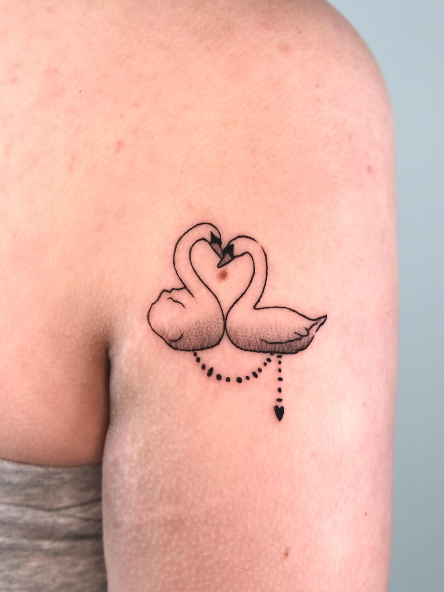 Swans forming heart dotwork tattoo on the shoulder by Elana Hites